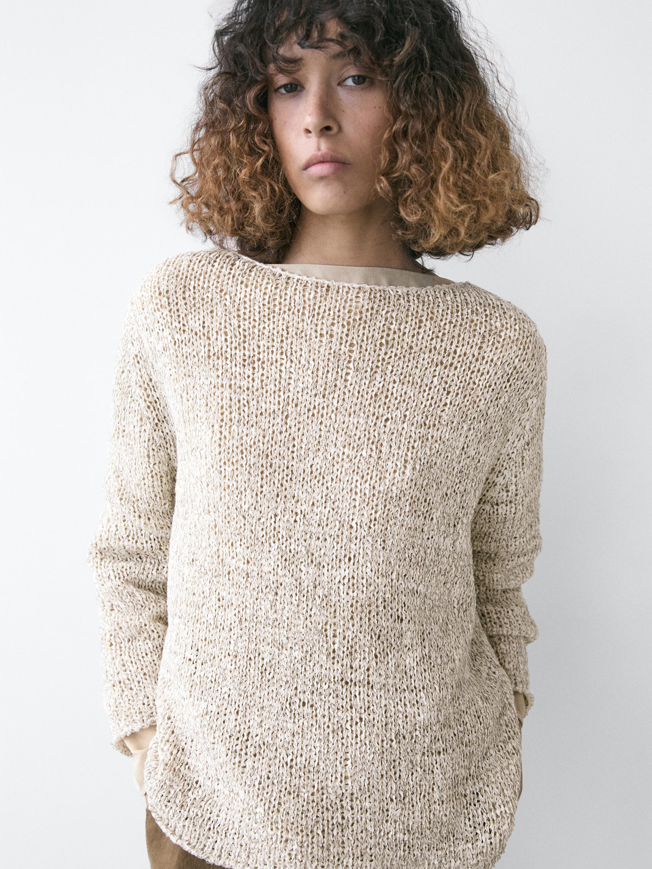 Bej renkli, kayık yakalı, uzun kollu örgü kazağın orta plan çekimi.