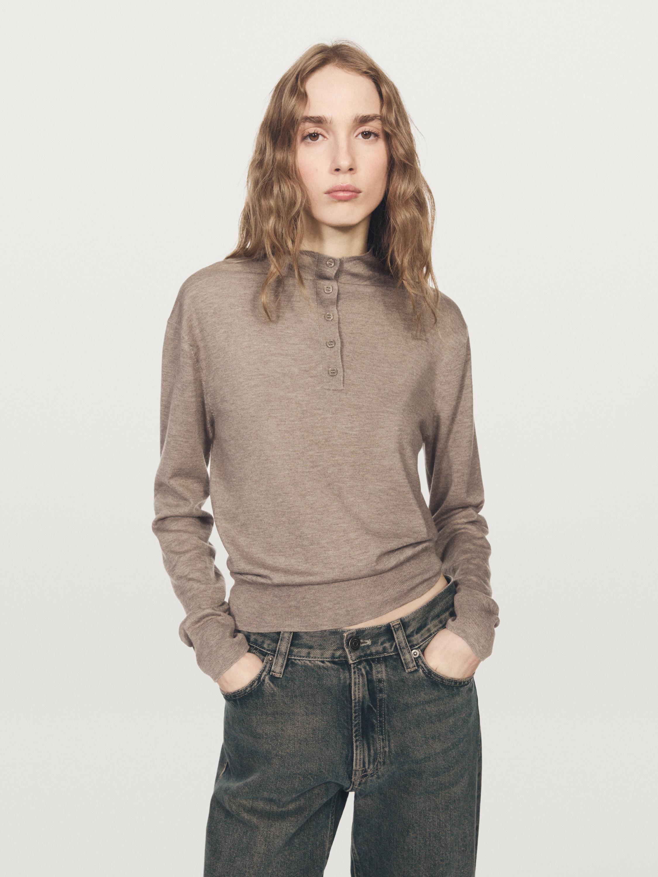 Conjunto de jersey crudo medio con cuello perkins abotonado y jeans oscuros con bolsillos laterales.