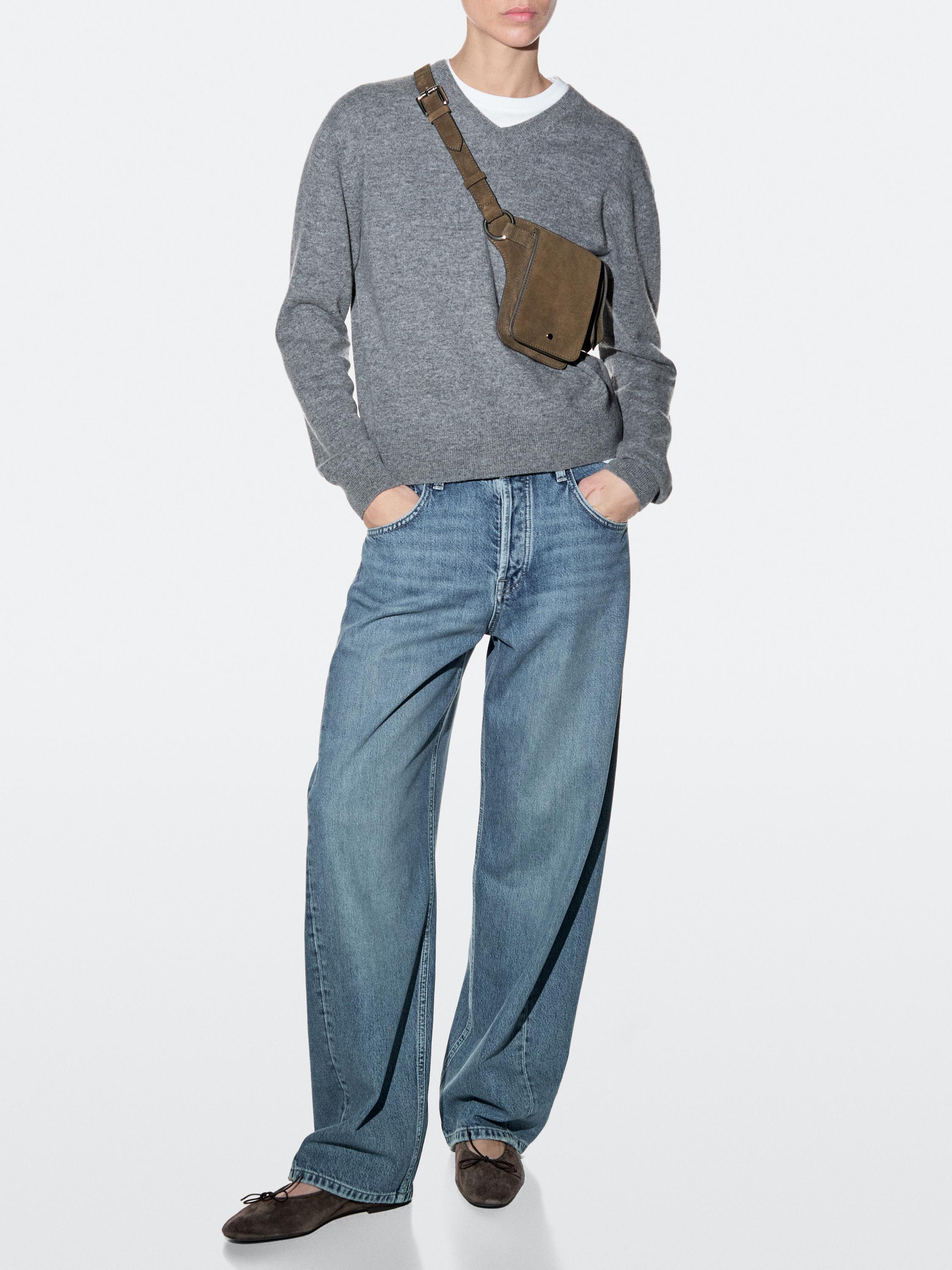 Khaki fanny pack set, gray sweater, white t-shirt, blue wide-leg jeans, and brown shoes.