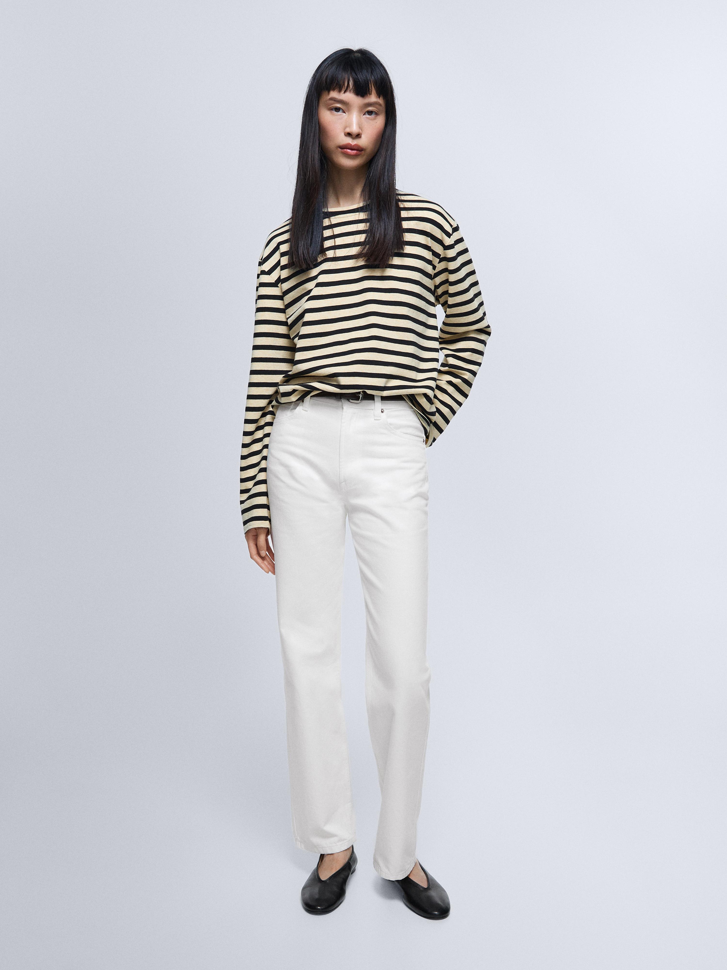 Sæt med højtaljede hvide ripped jeans og sort- og beigestribet langærmet T-shirt.