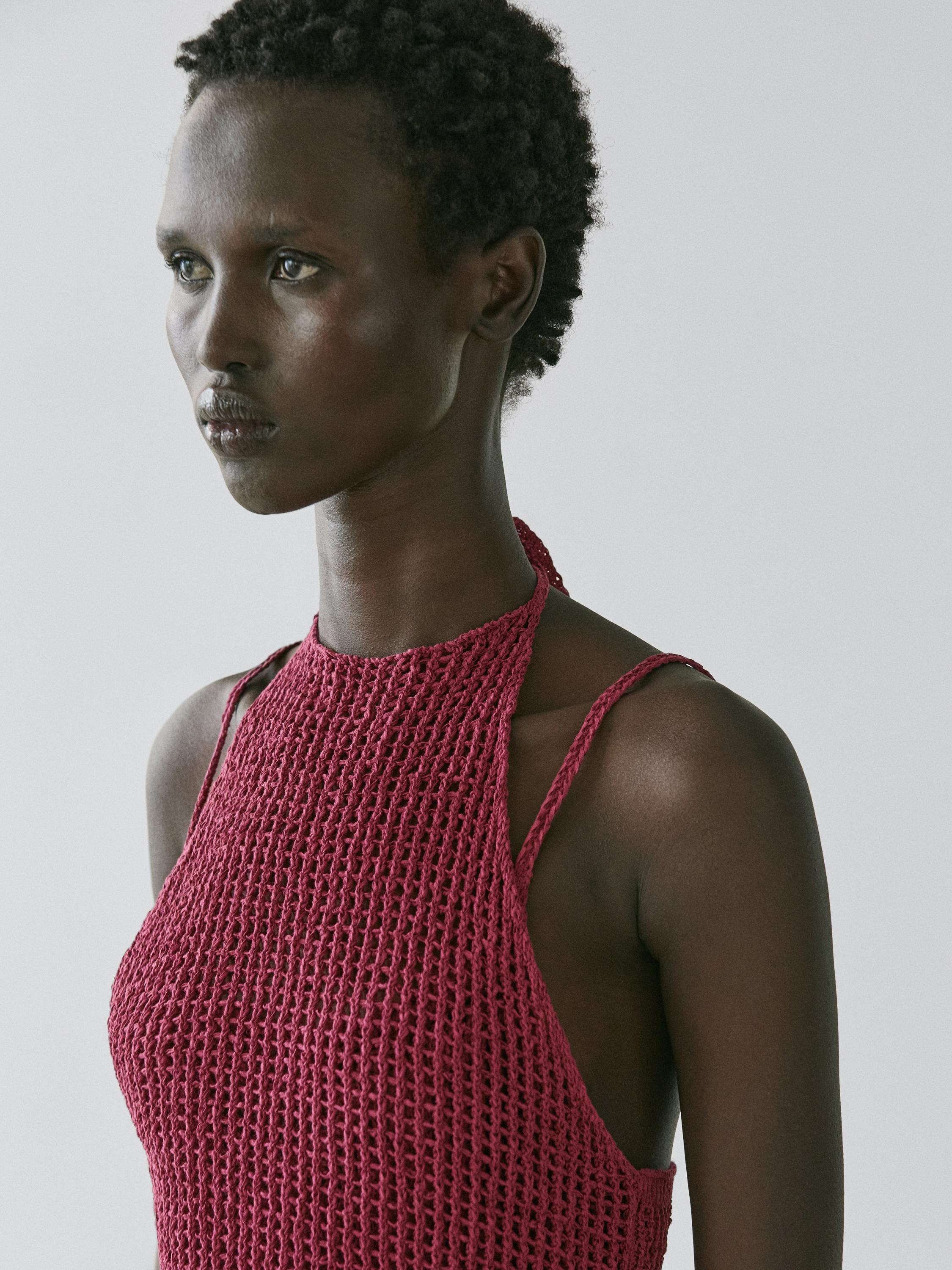 Półzbliżenie szydełkowego topu w kolorze malinowym z cienkimi ramiączkami i dekoltem typu halter.