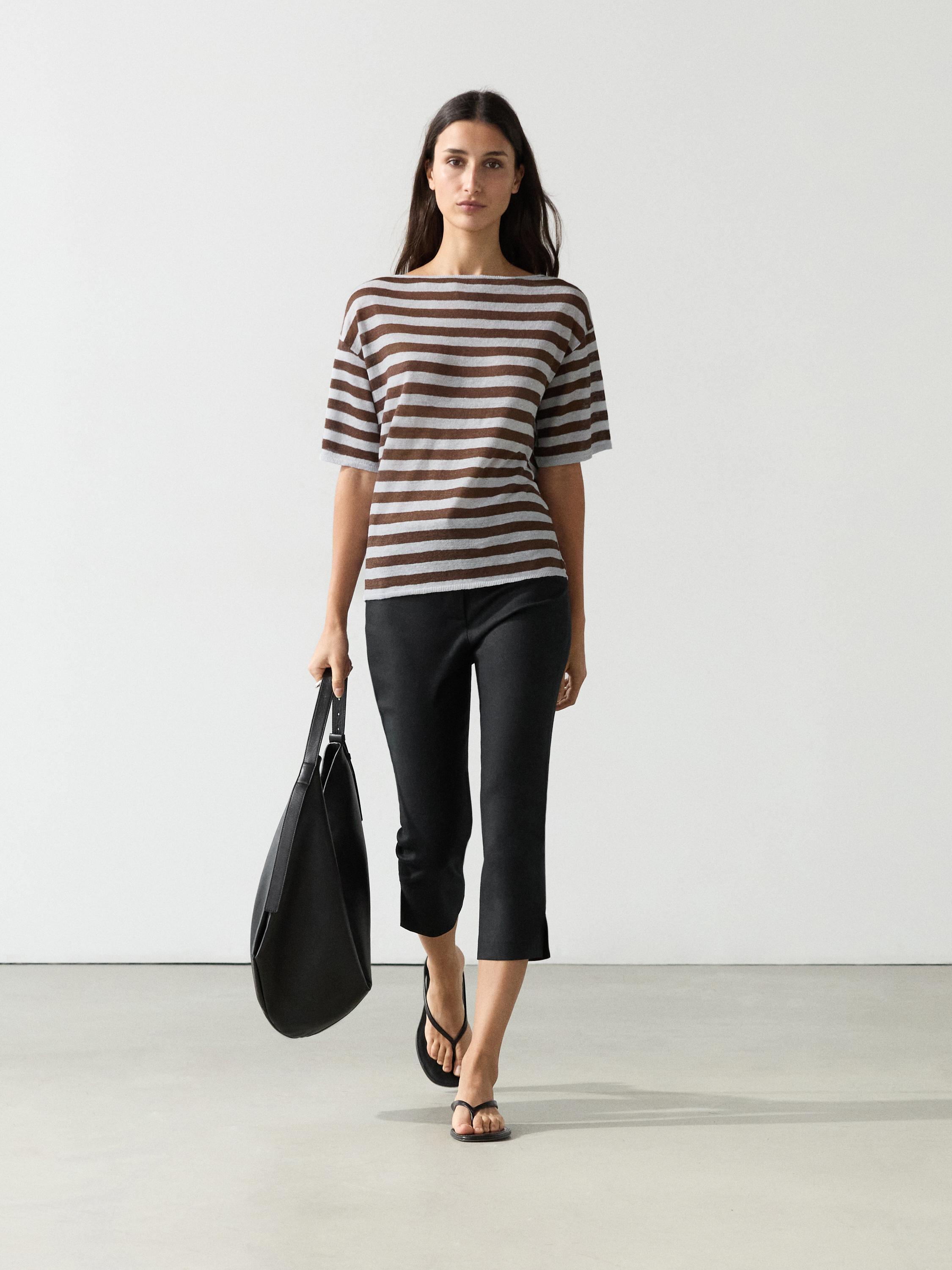 Ensemble composé d'un tee-shirt à rayures marron et bleu ciel, à manches courtes et col bateau, d'un pantalon noir et de sandales.