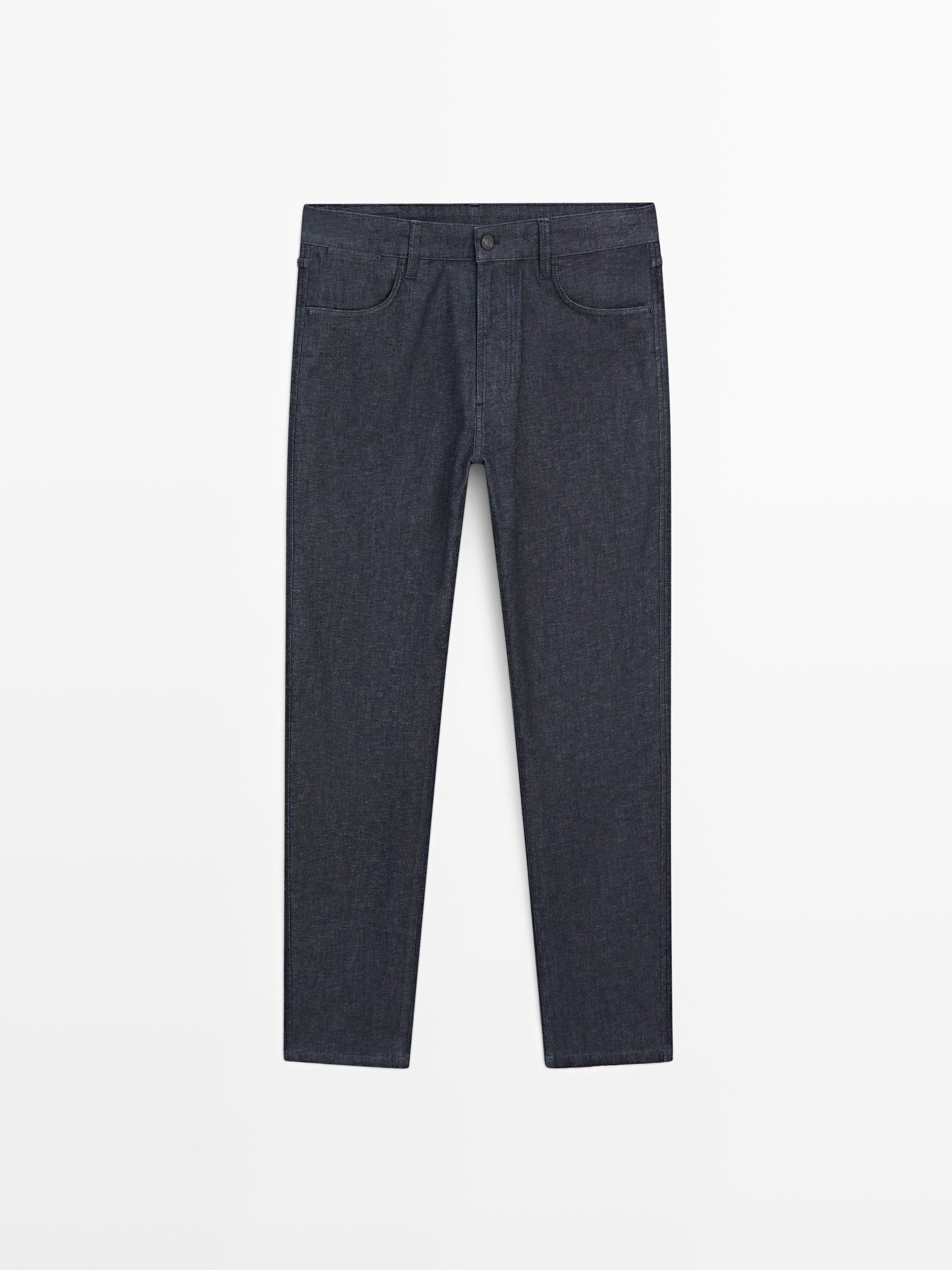 Aurrealdeko ikuspegia: slim fit estiloa duten jeans urdin ilunak, aurreko eta atzeko poltsikoekin, botoi eta kremailera itxierarekin.