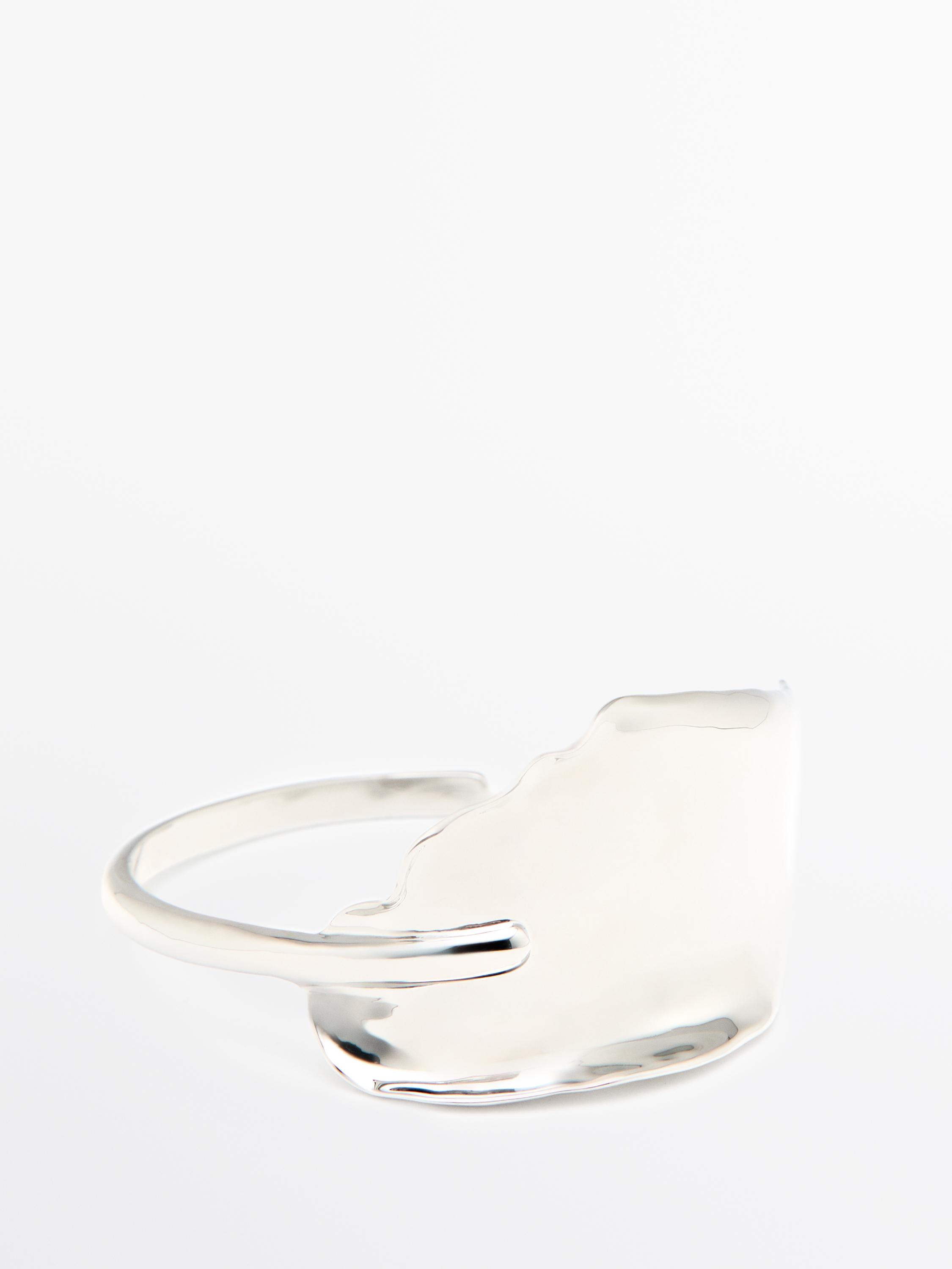 Pulseira larga de prata com textura ondulada e design assimétrico.