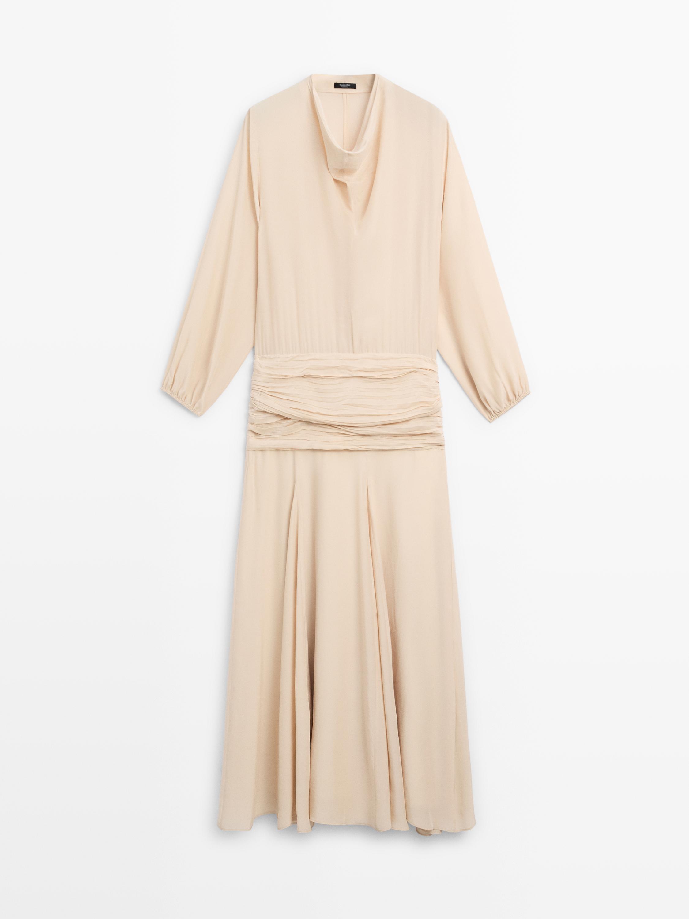 Vue de face d'une robe longue couleur avec un col drapé, des manches longues et un détail froncé à la taille.