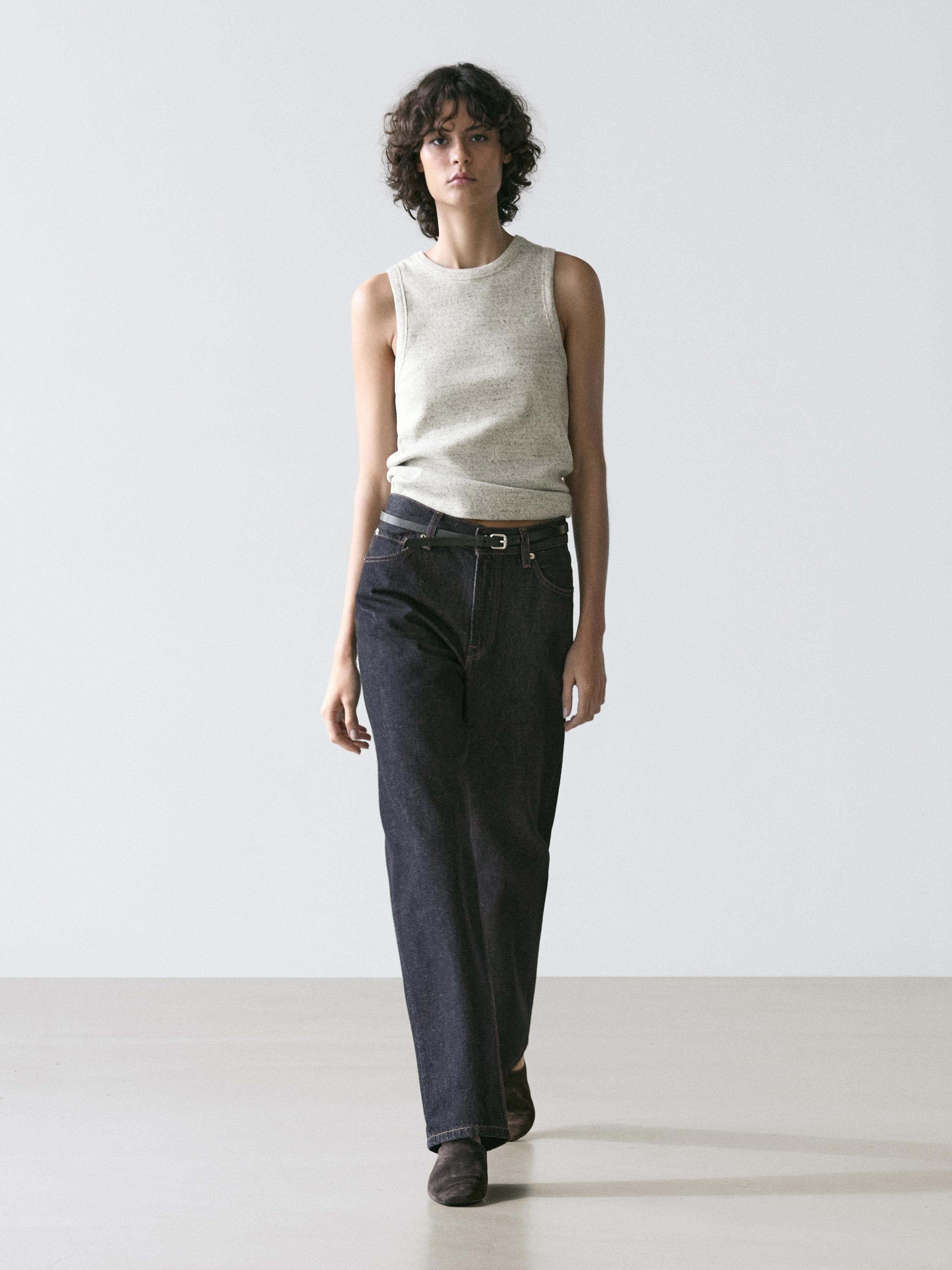 Set van grijze mouwloze top en donkere rechte broek met zwarte riem.