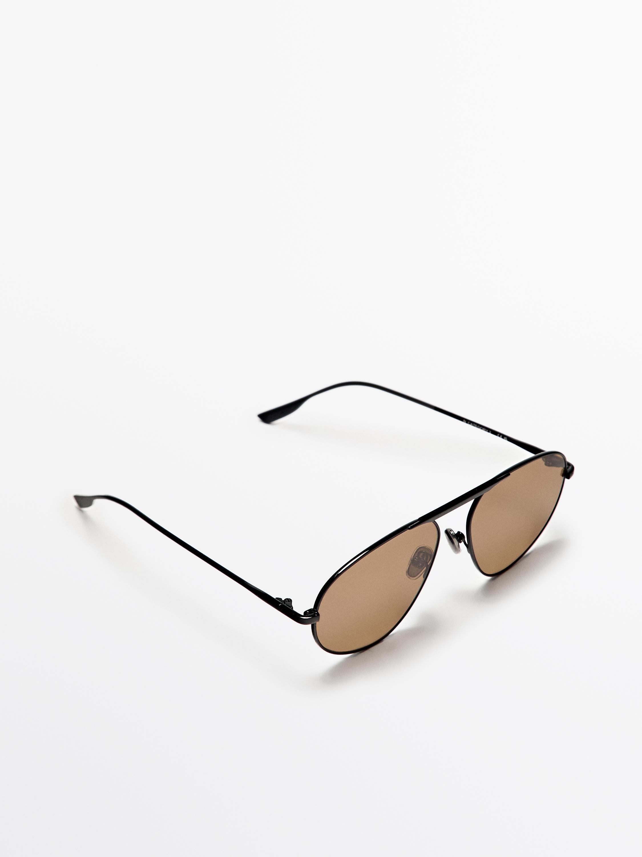 Vue frontale de lunettes de soleil noires avec verres marron, pont fin et branches fines. Dimensions: 58-15-148 mm.