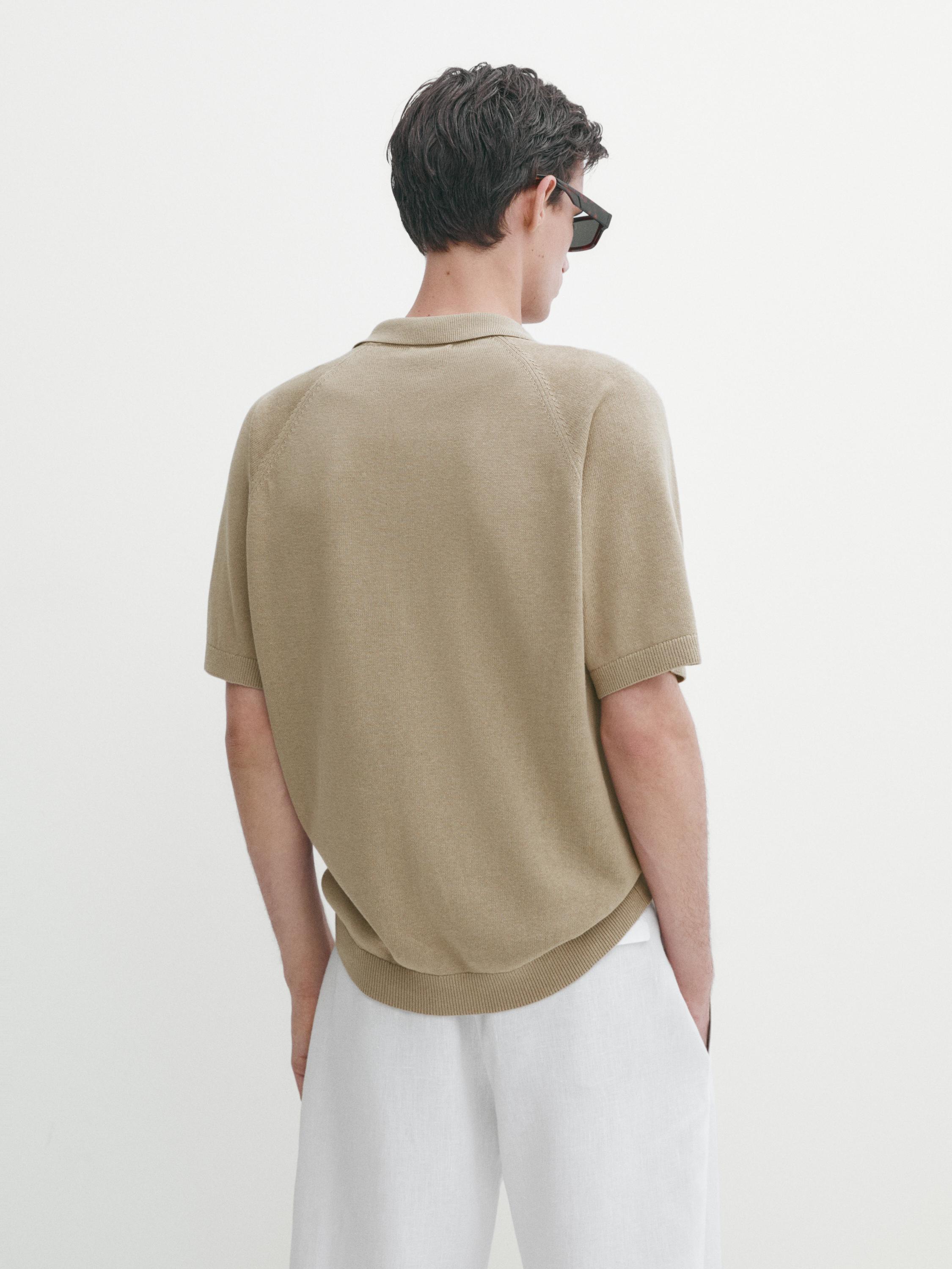 Vue arrière d'un polo beige à manches courtes et d'un pantalon blanc.