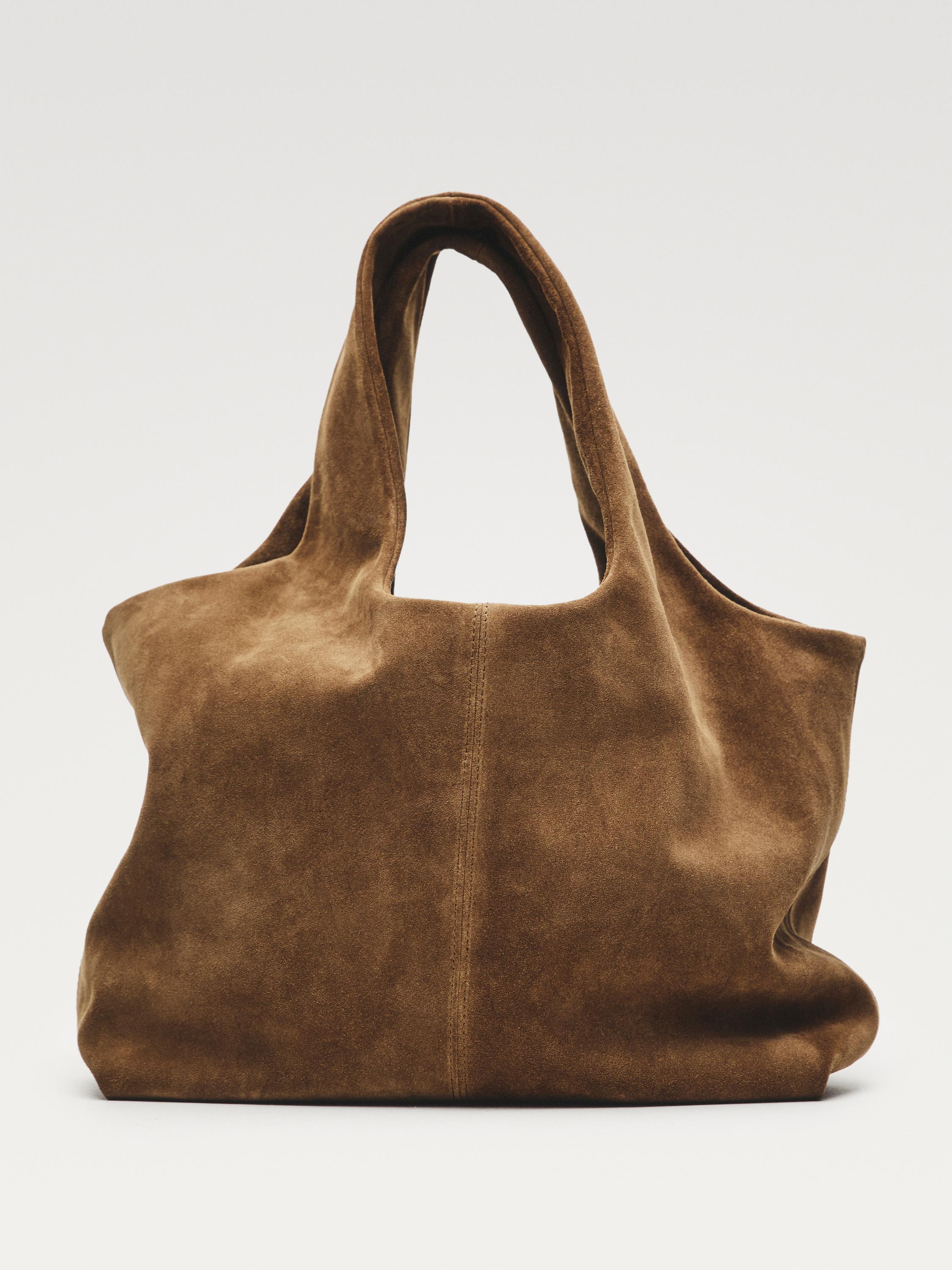 Front view of a sand-colored handbag with long handles and visible central stitching.