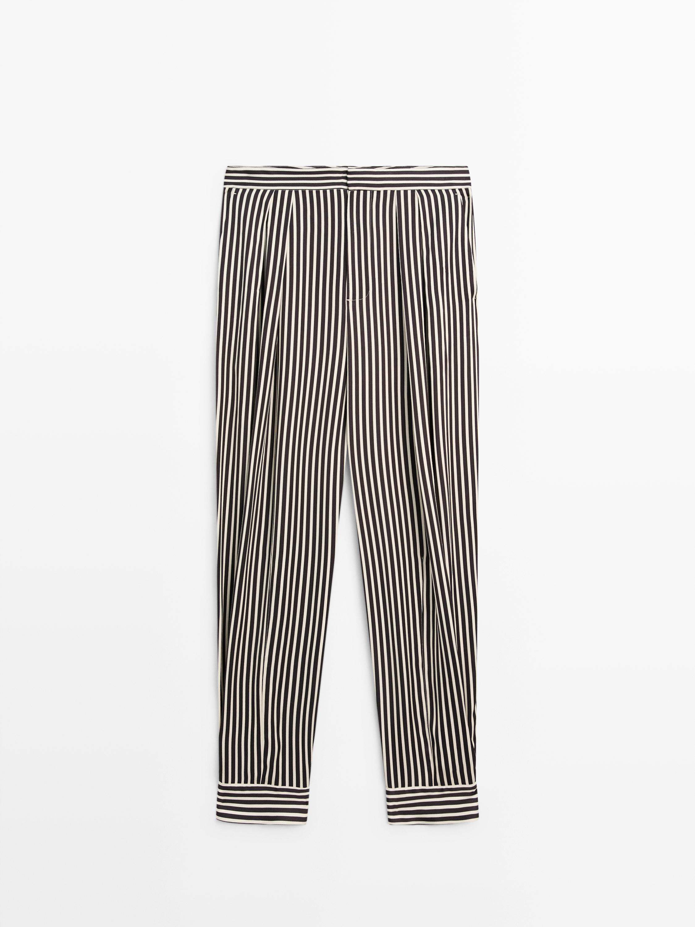 Front view of black and white pants with vertical stripes and pleats.