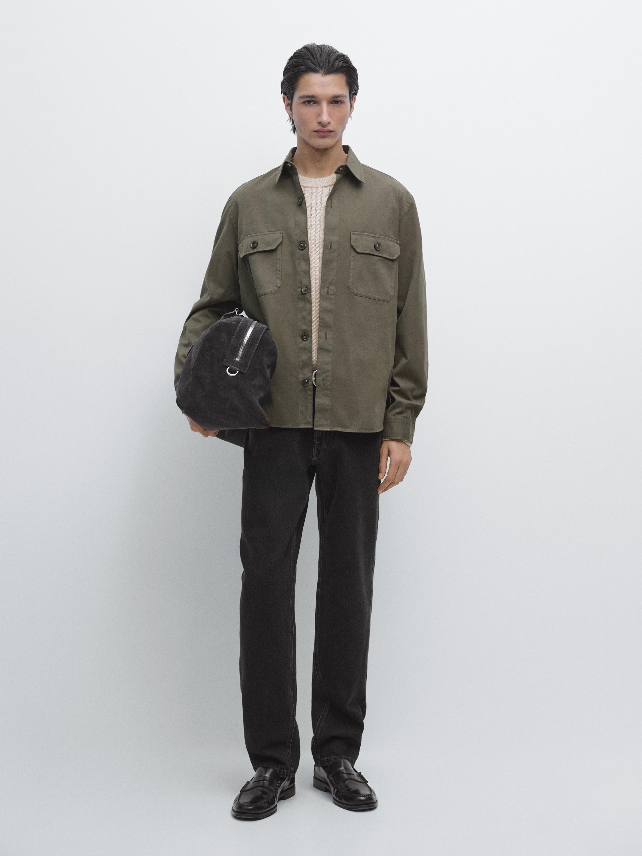 Green overshirt set with front pockets, beige sweater, dark pants, and black loafers.