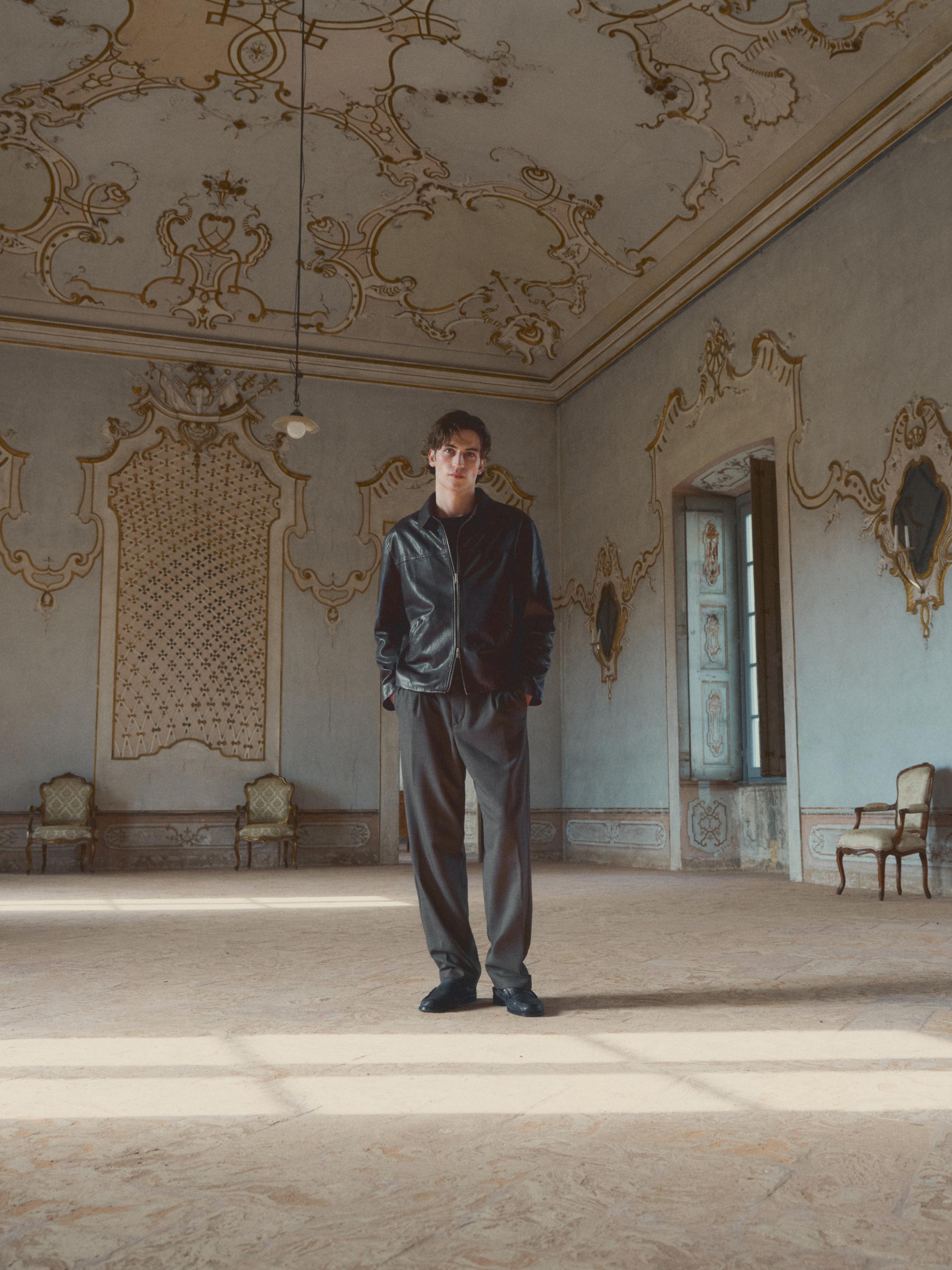 Set aus brauner Nappaleder-Effekt-Blousonjacke und geraden dunklen Hosen.