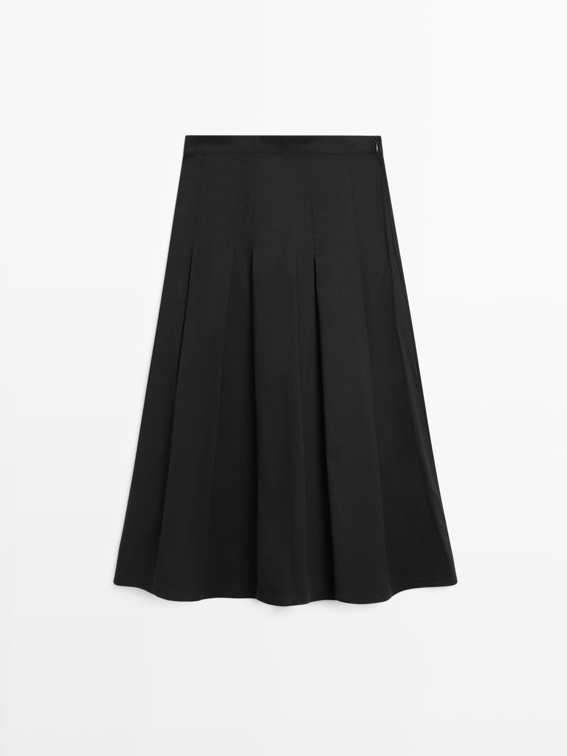 Vista frontal de falda negra con pliegues y corte midi.