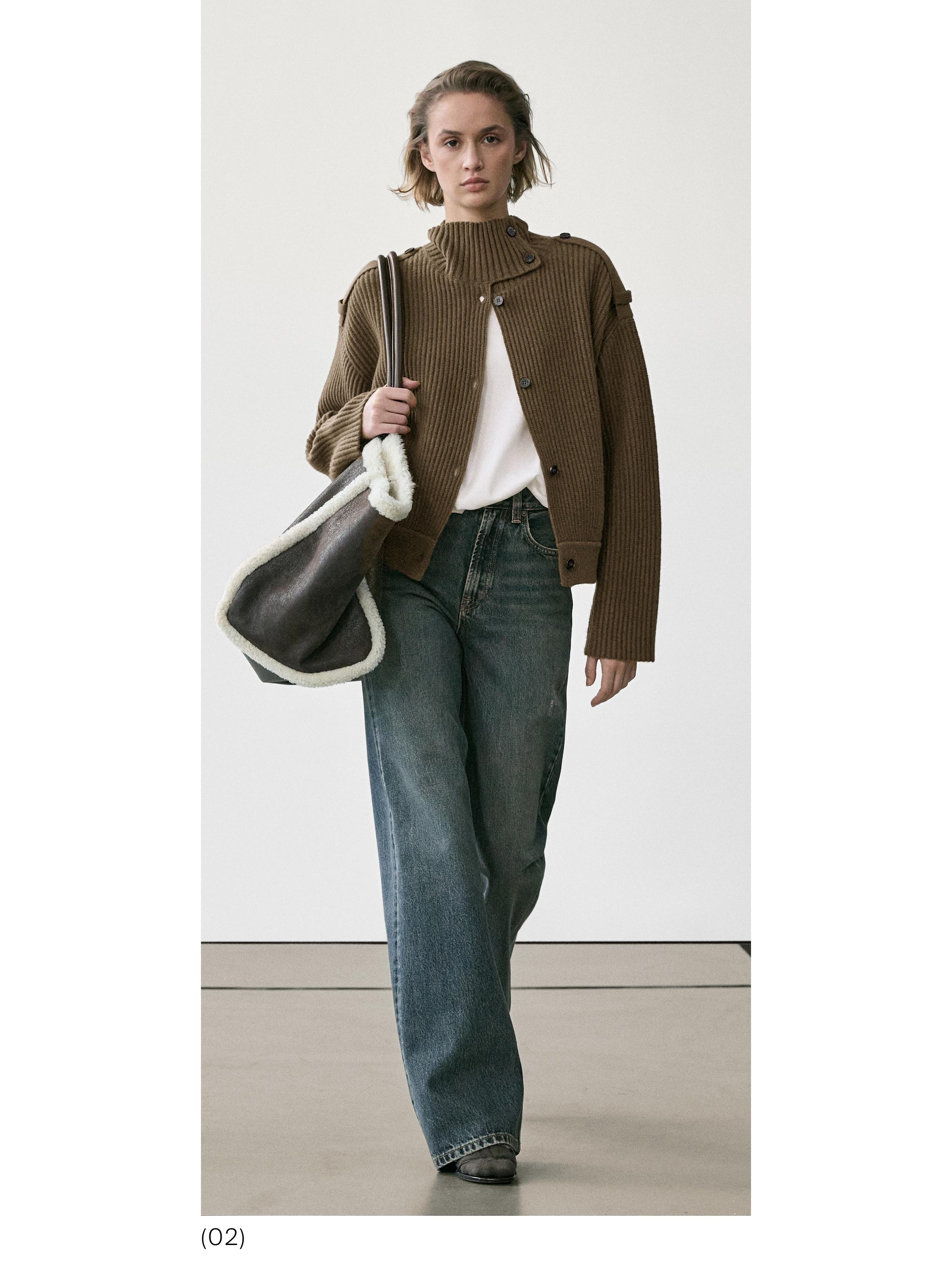 Conjunto de chaqueta café de punto con botones, playera blanca, jeans anchos azules y bolsa grande con borde blanco.