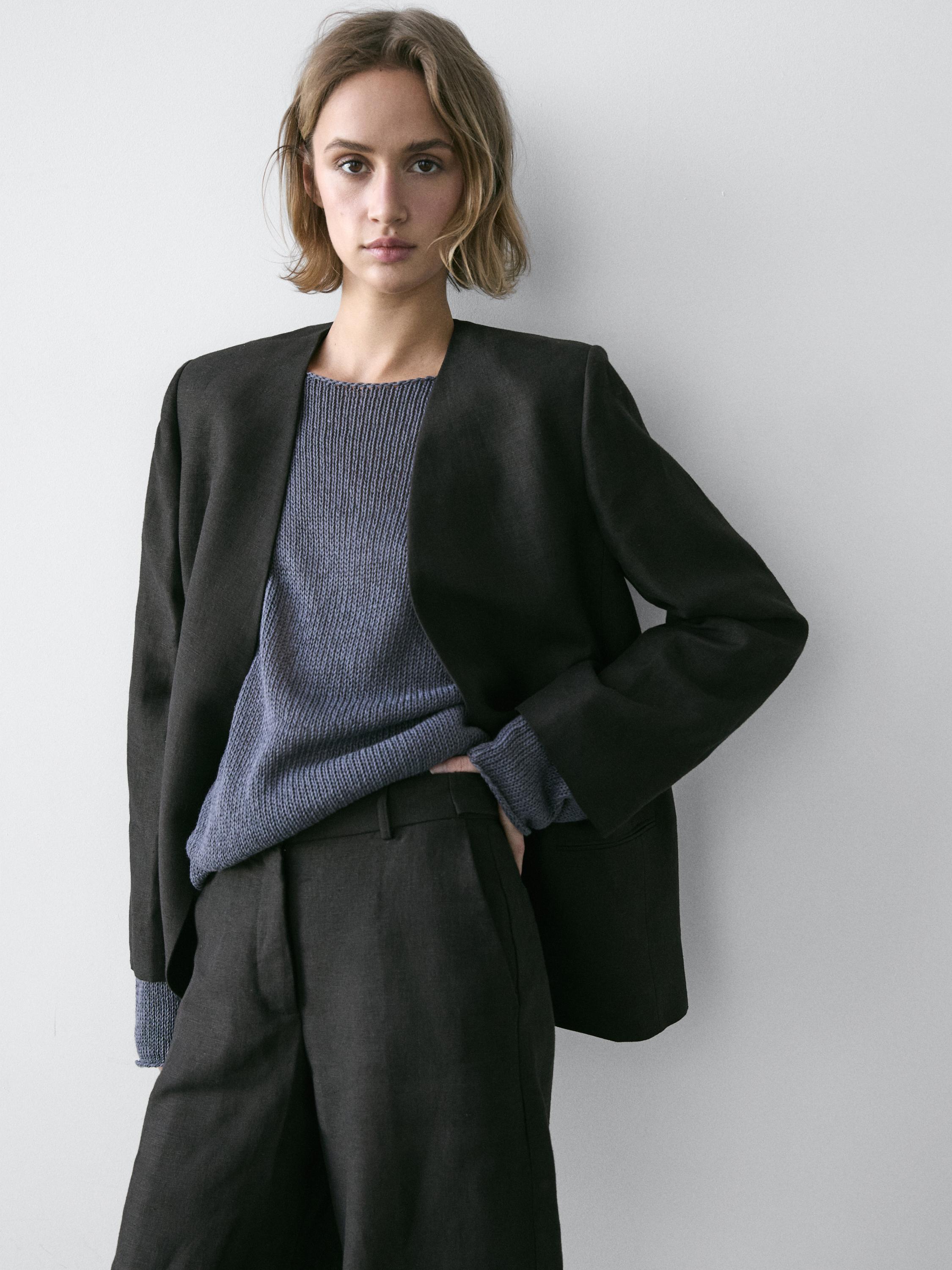 Black blazer set without lapels, gray knit sweater, and black pants with side pockets.