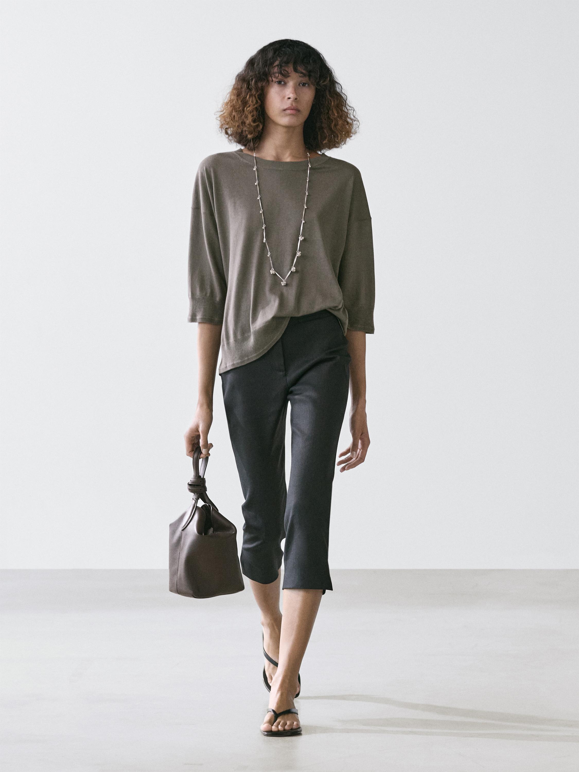 Conjunto de jersey marrón topo de manga corta y pantalones negros capri, con bolso marrón y sandalias negras.