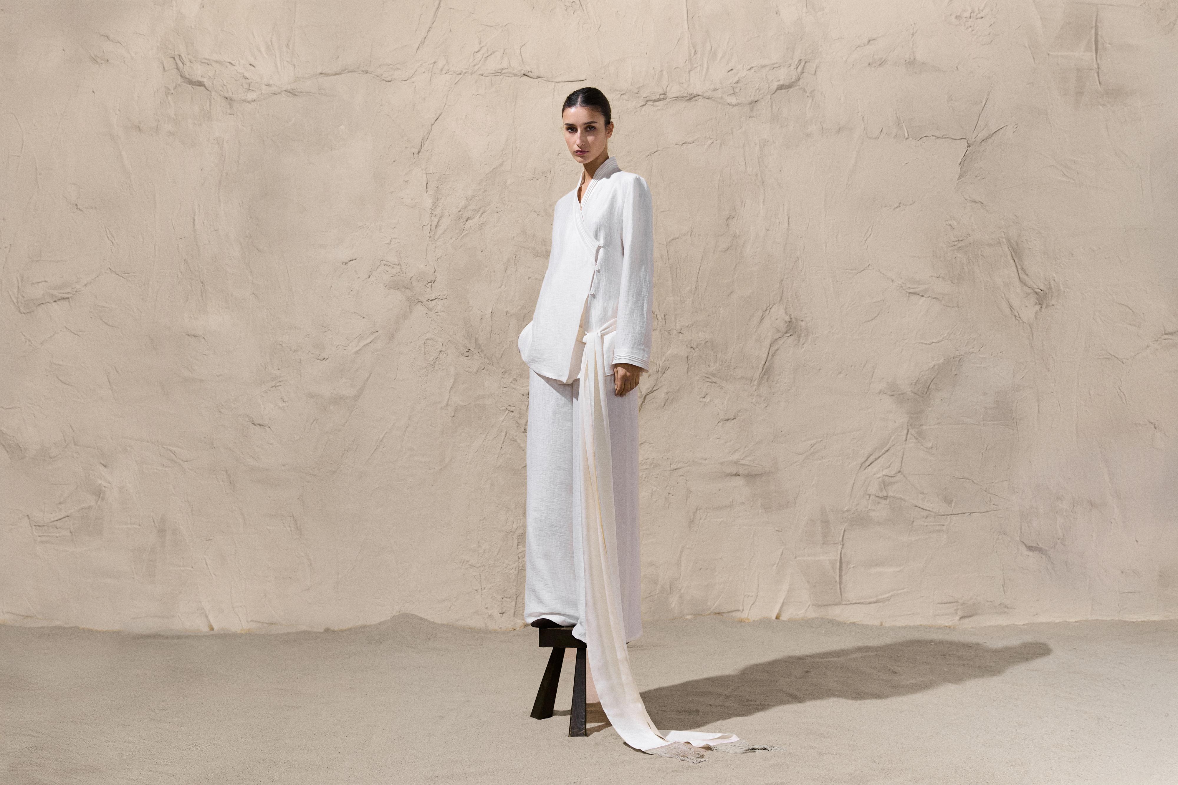 Setelan blus putih lengan panjang dengan ikat samping dan celana panjang wide-leg yang serasi.