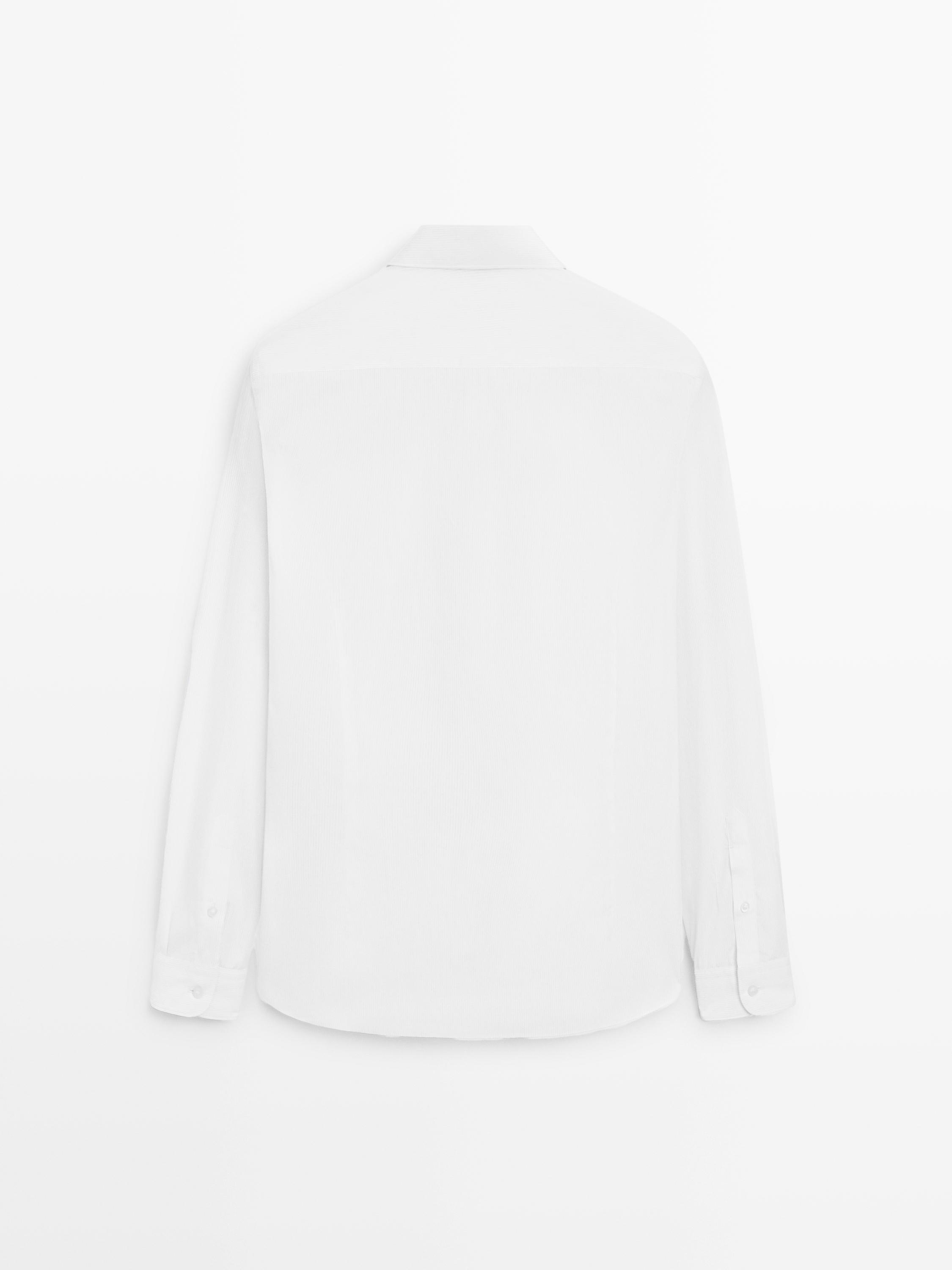 Vista posterior de camisa blanca de manga larga con puños abotonados.