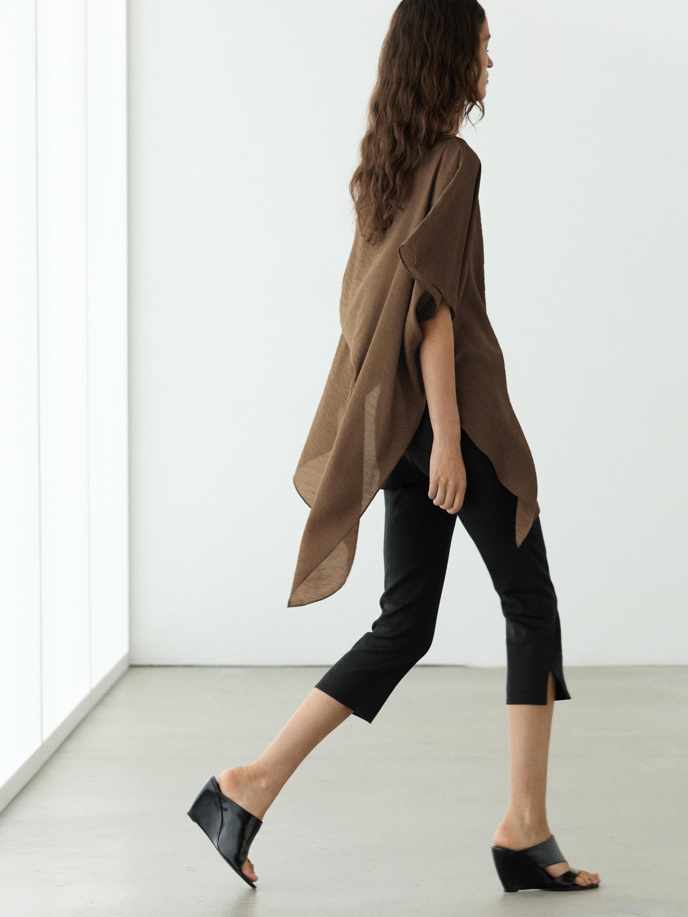 Conxunto de blusa marrón solta e pantalón capri negro con aberturas laterais.