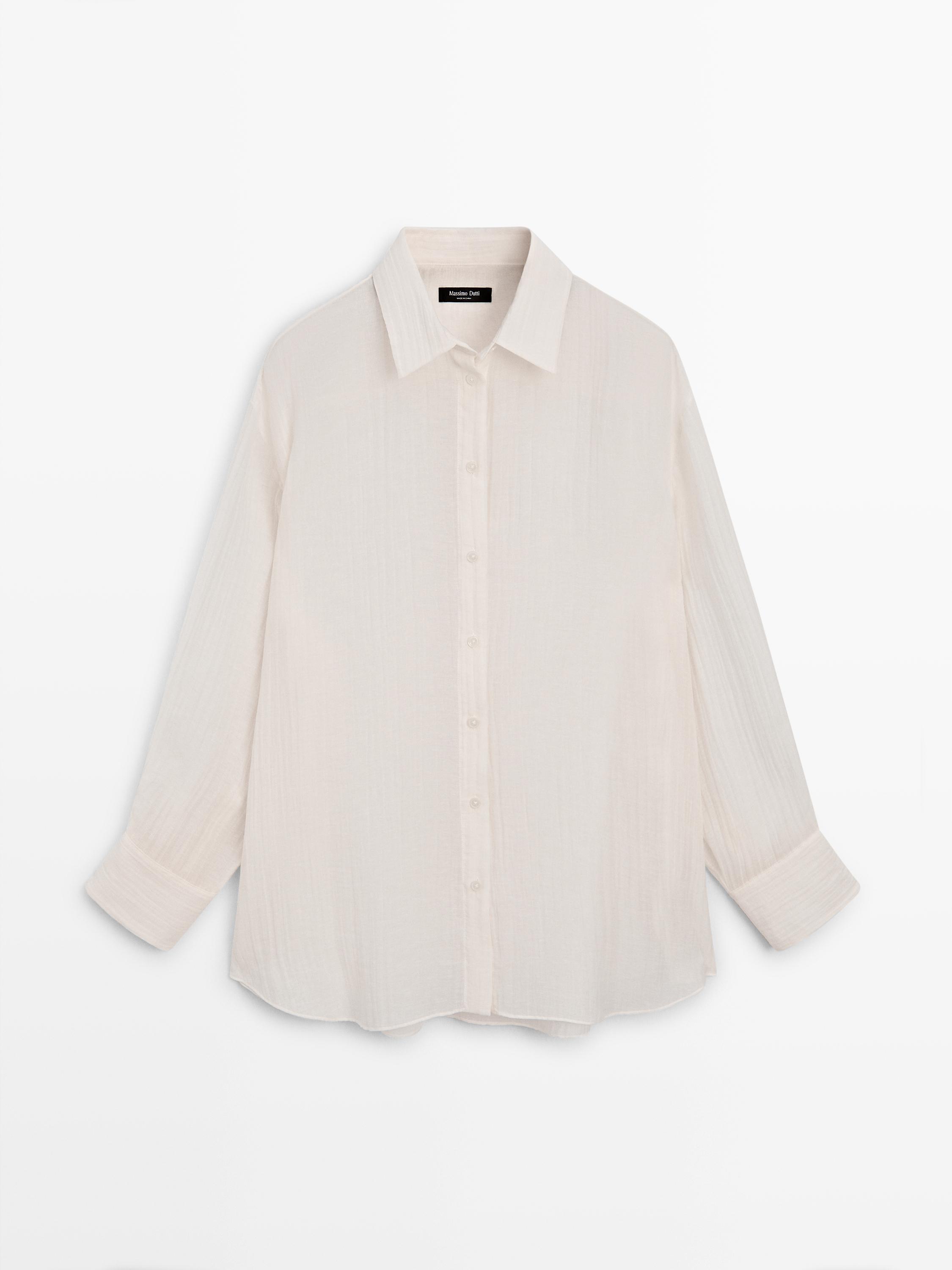Front view of an ivory overshirt with pleated detail, central buttoning, and long sleeves with cuffs.