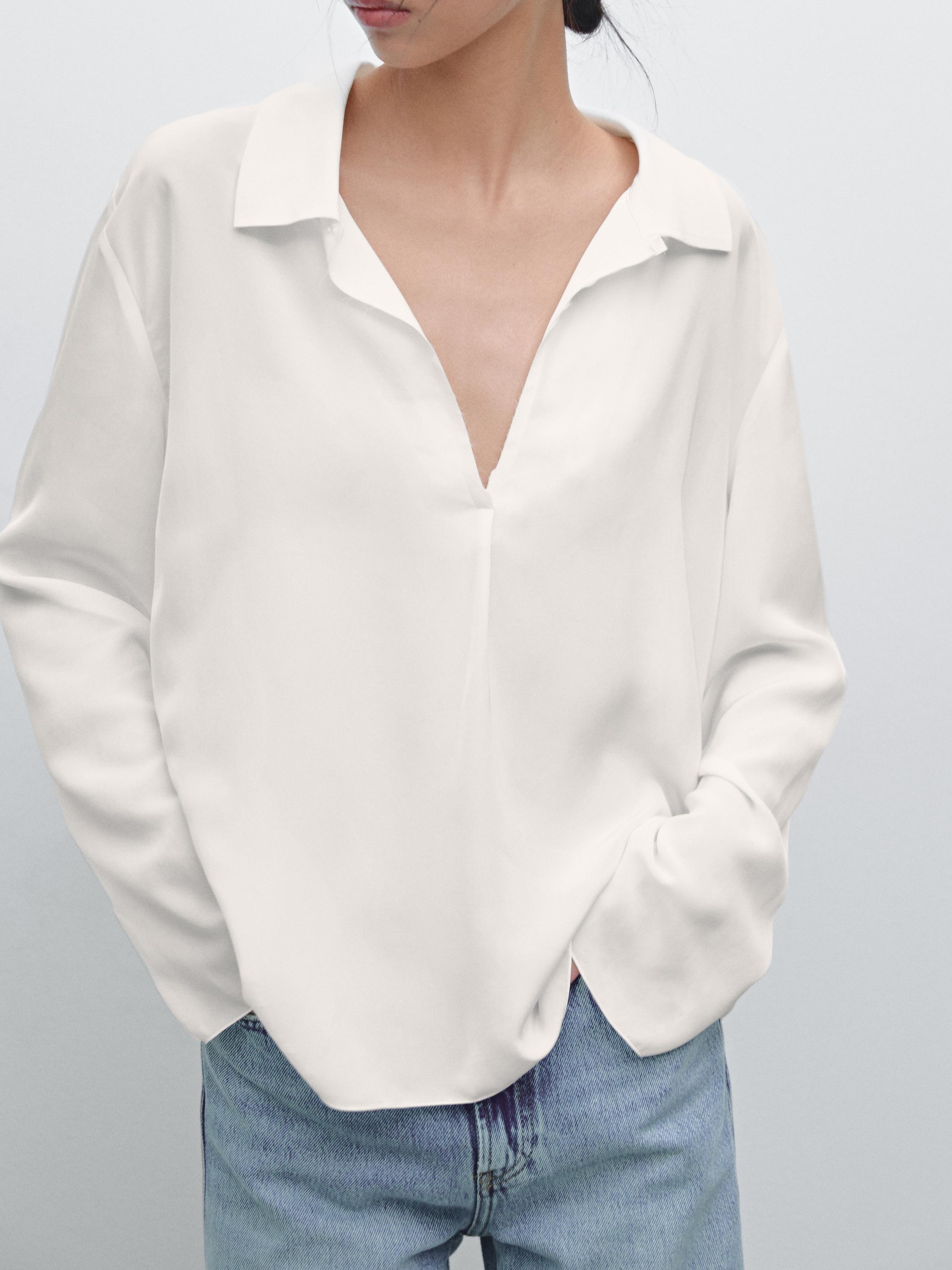 Plan moyen d'une chemise blanche avec un col ouvert et un jean bleu visible.