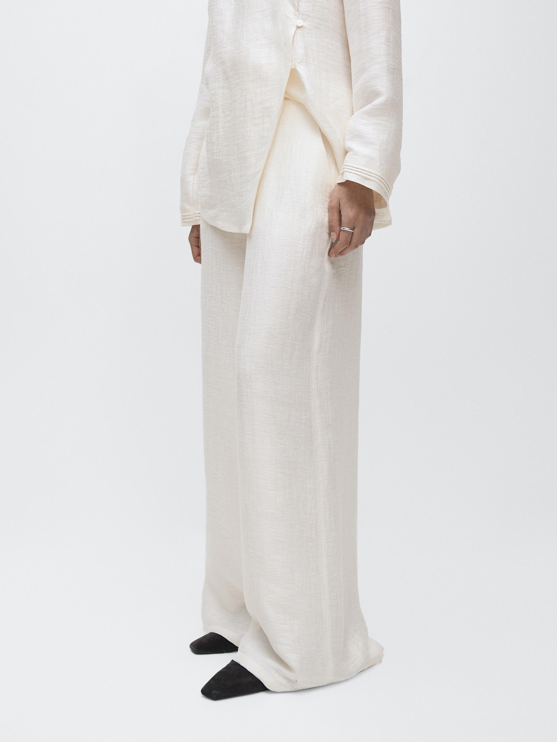 لقطة متوسطة لبنطال أبيض مائل للصفرة واسع الساقين، بخصر عالٍ وبدون جيوب ظاهرة.