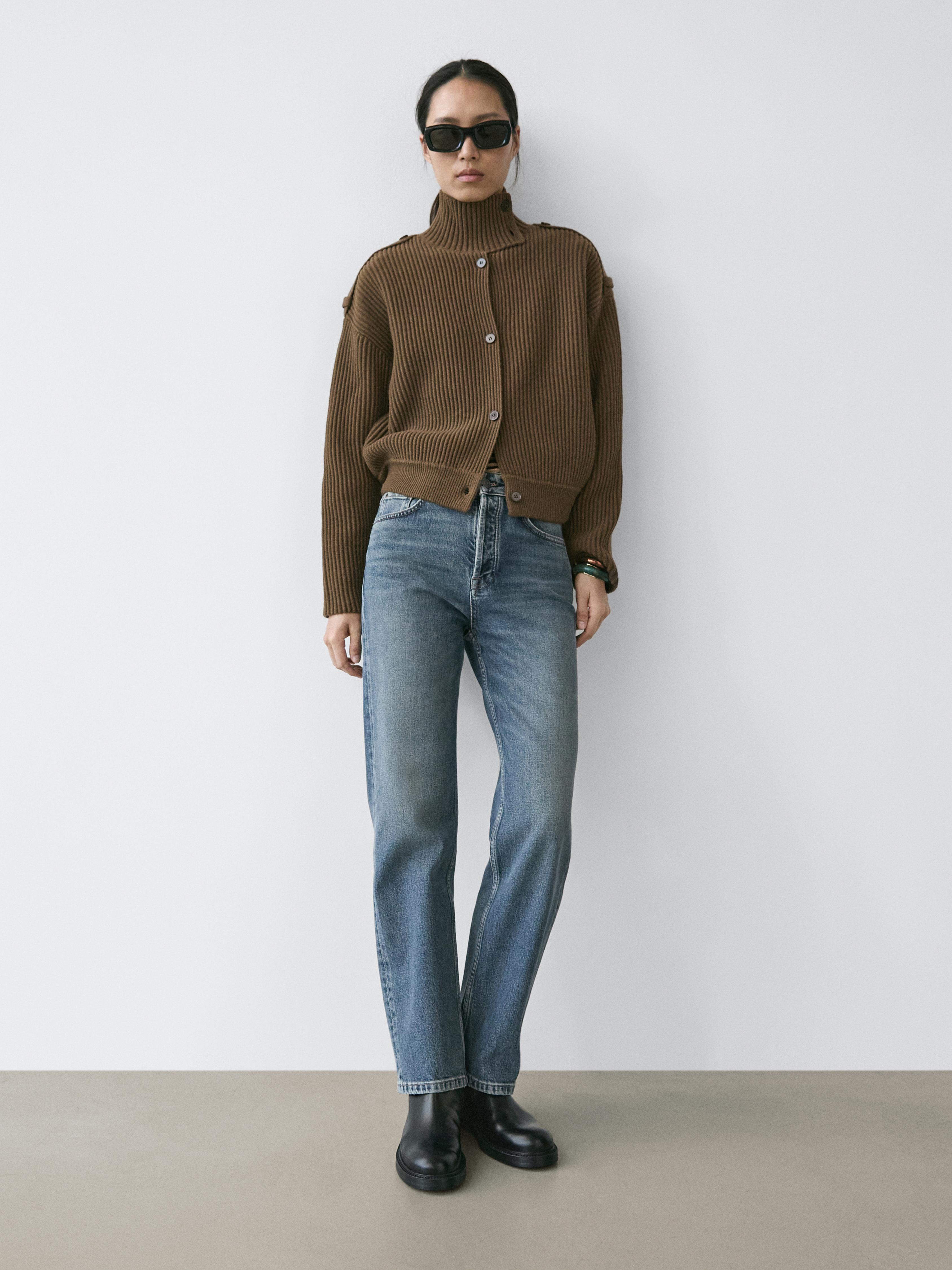 Completo di cardigan kaki in maglia con bottoni e jeans blu a gamba dritta.