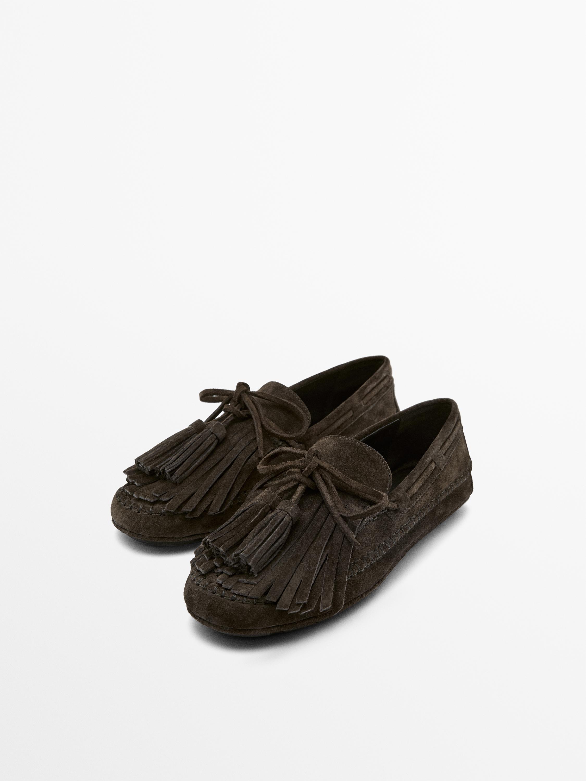 Mocassins marron à franges et pompons sur le dessus, design classique et coutures visibles.