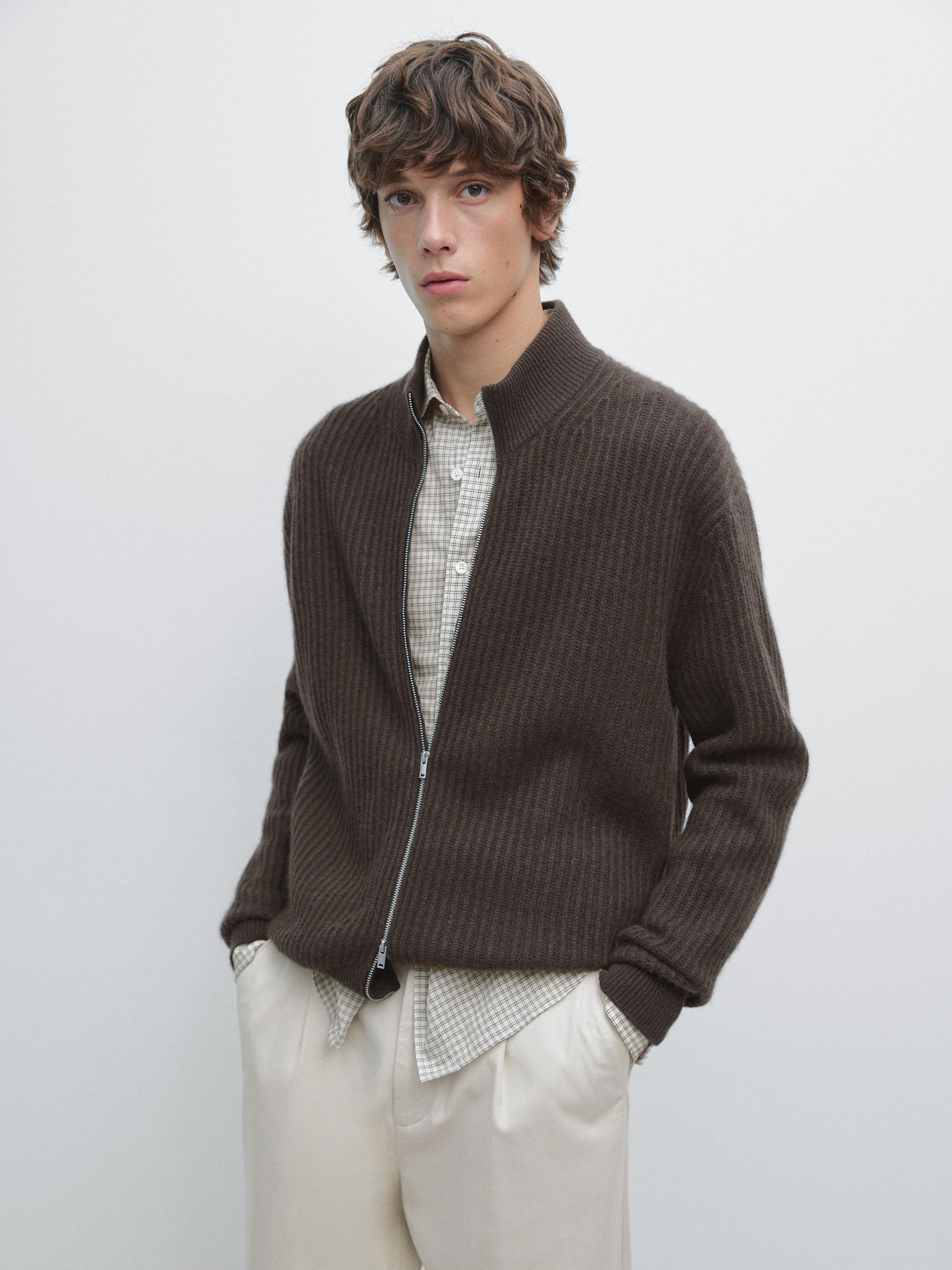 Brown marled cardigan set with zipper and side pockets, over a beige plaid shirt and light-colored pants.