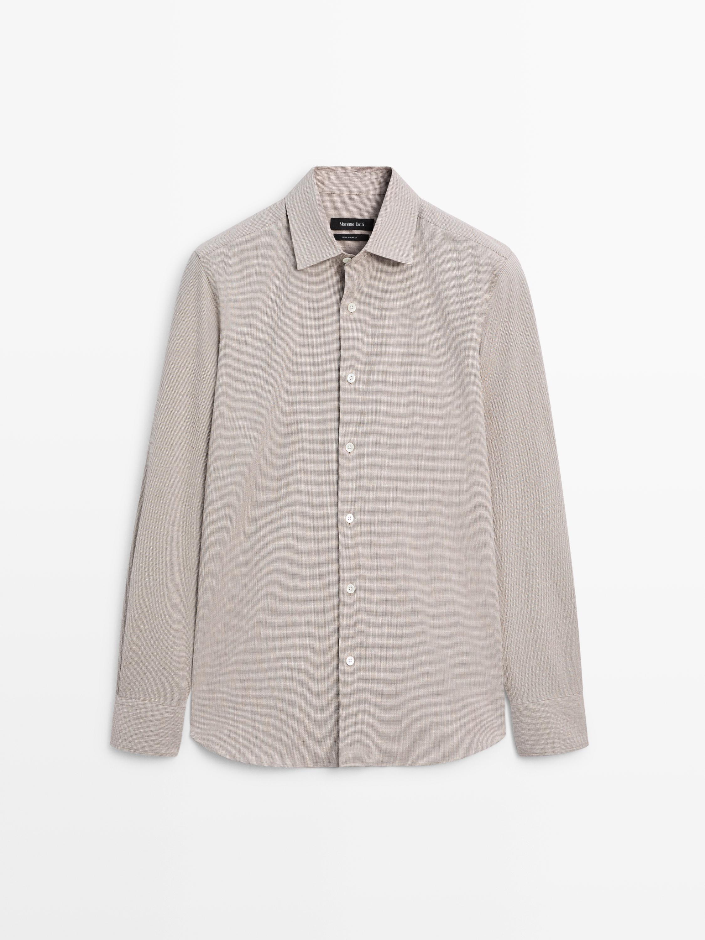 Vue de face d'une chemise beige à manches longues avec col classique et boutonnage central.