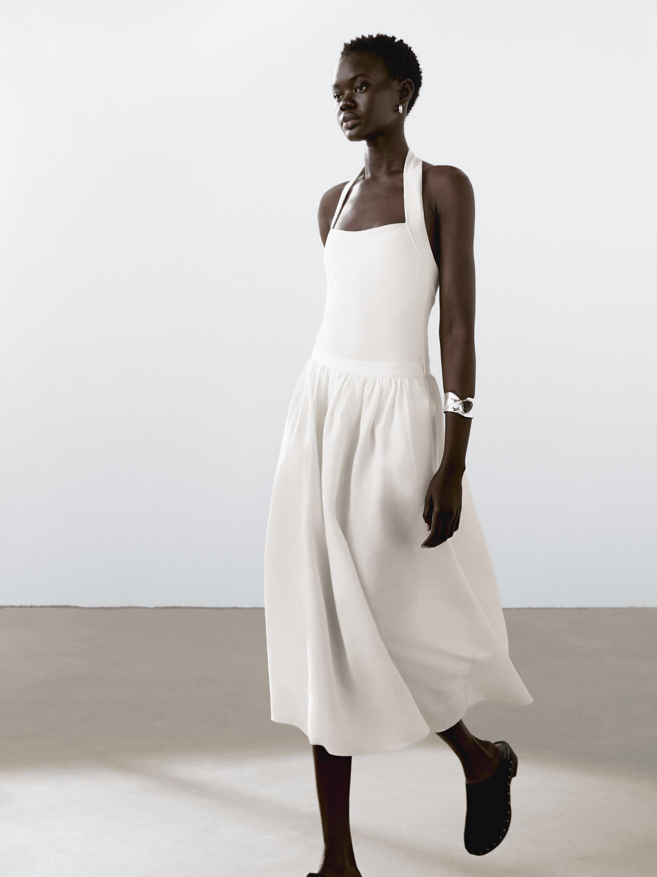 طقم فستان أبيض بحمالات وتنورة ميدي، مع حذاء أسود.