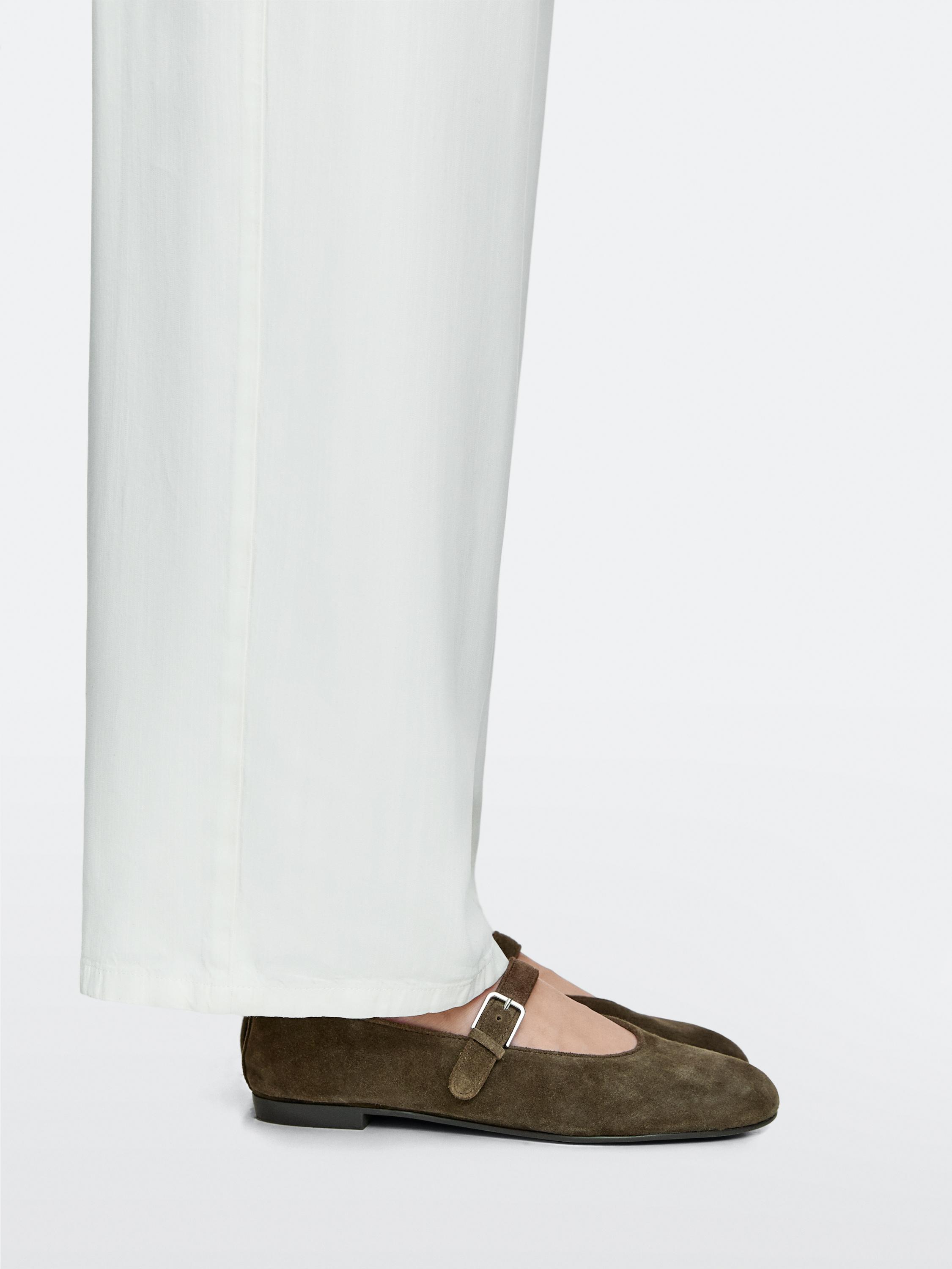 Πλάνο μέσο από χακί φλατ παπούτσια τύπου μπαλαρίνας με λουράκι και πλευρική αγκράφα.