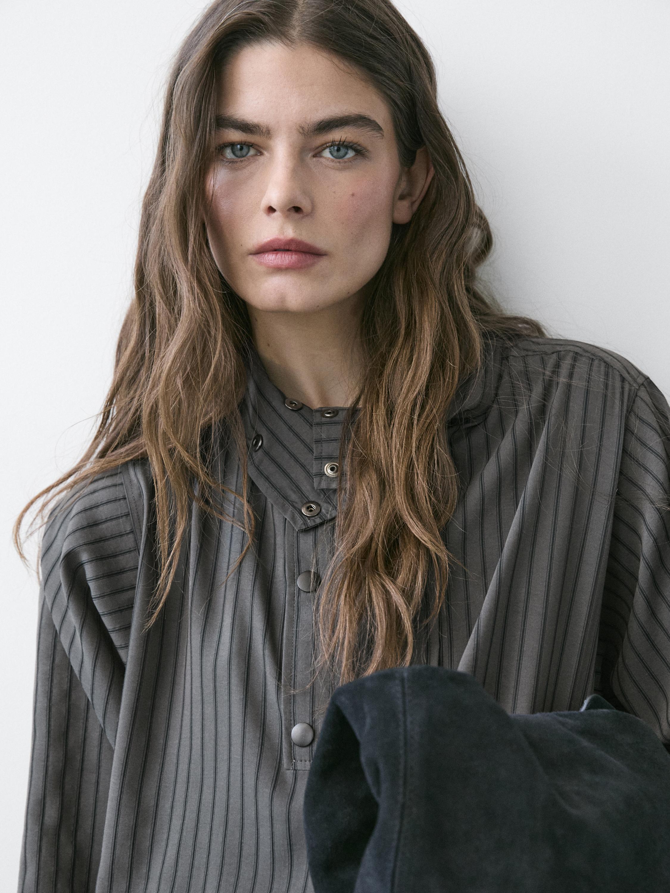 "Halflange opname van een soepelvallend grijs overhemd met strepen en knoopjes bij de kraag."
