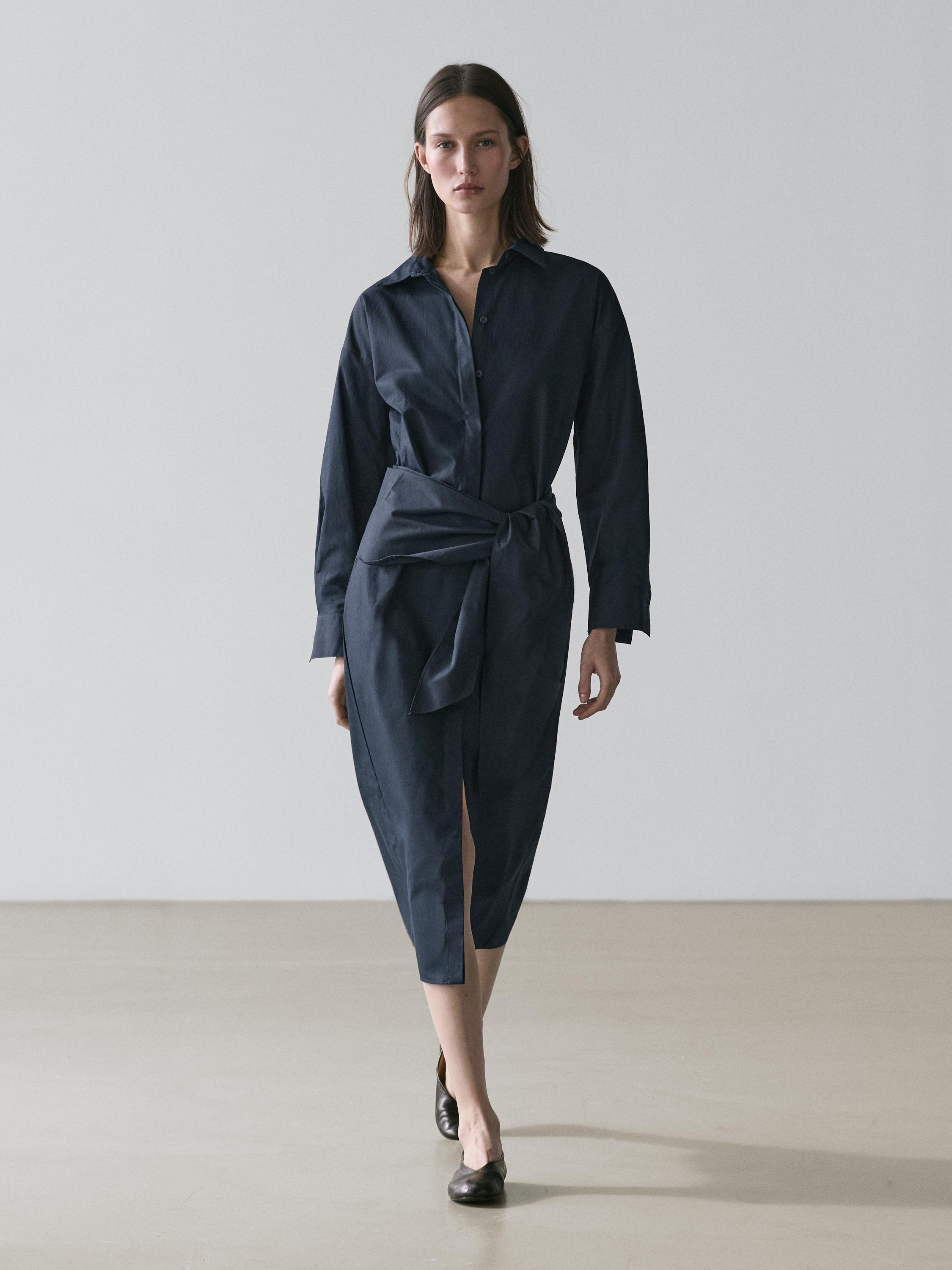 Komplet fustan blu midi tip këmishë, me detaj shalli në bel dhe të çarë përpara.