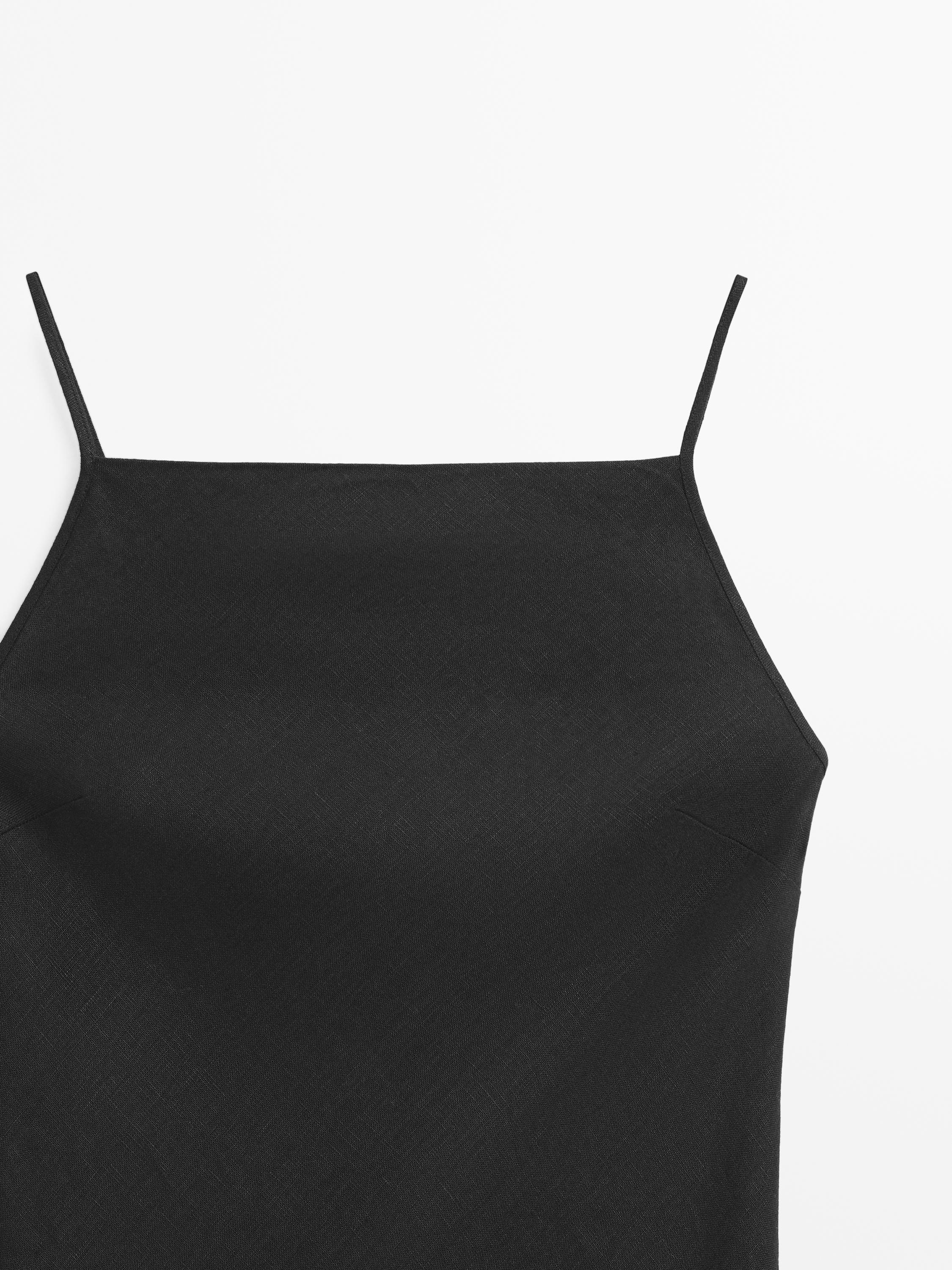 "Szczegół góry czarnej sukienki na cienkich ramiączkach."