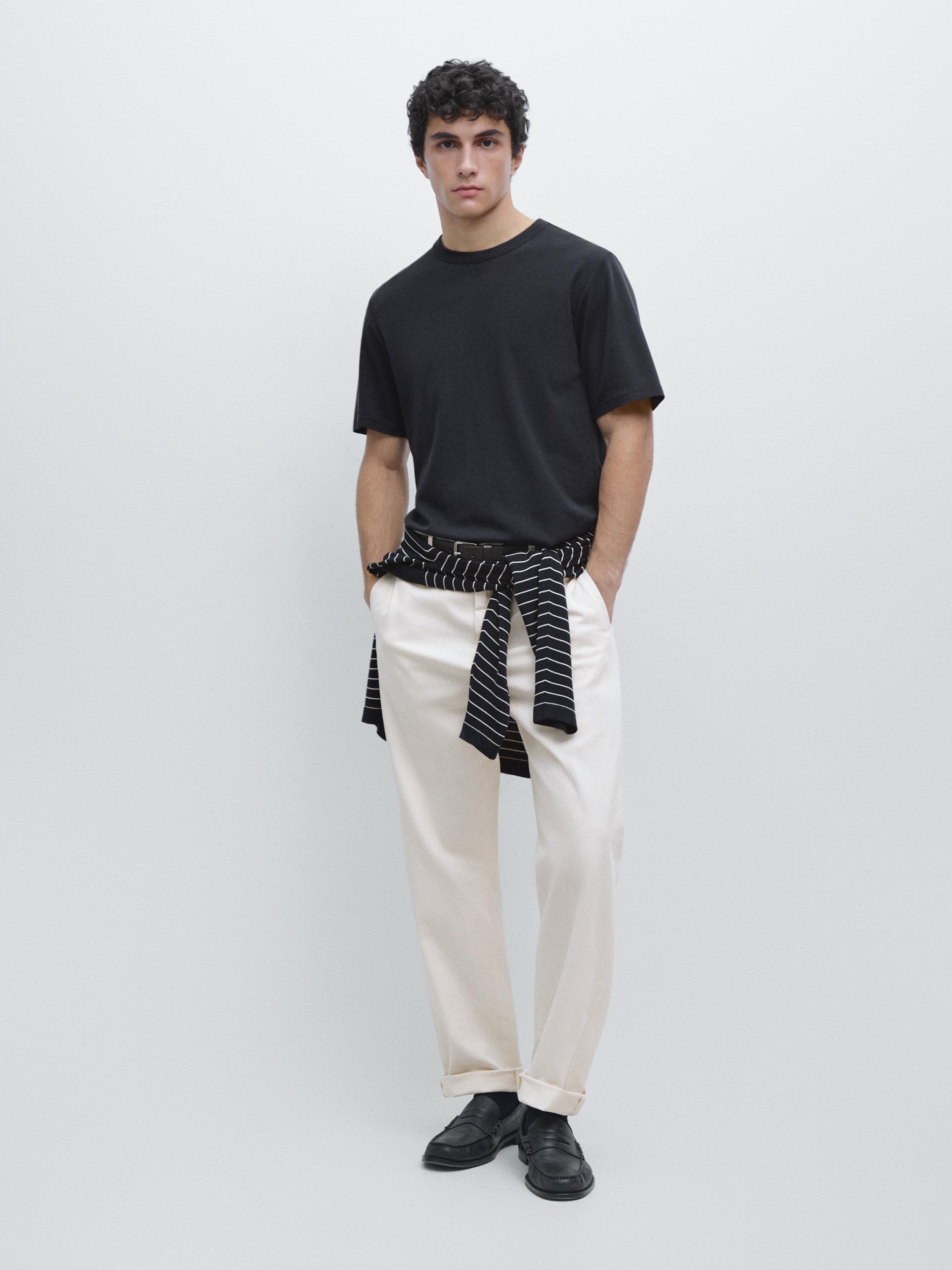 Set aus marineblauem Kurzarm-T-Shirt, beiger Hose mit Seitentaschen und schwarzen Schuhen.