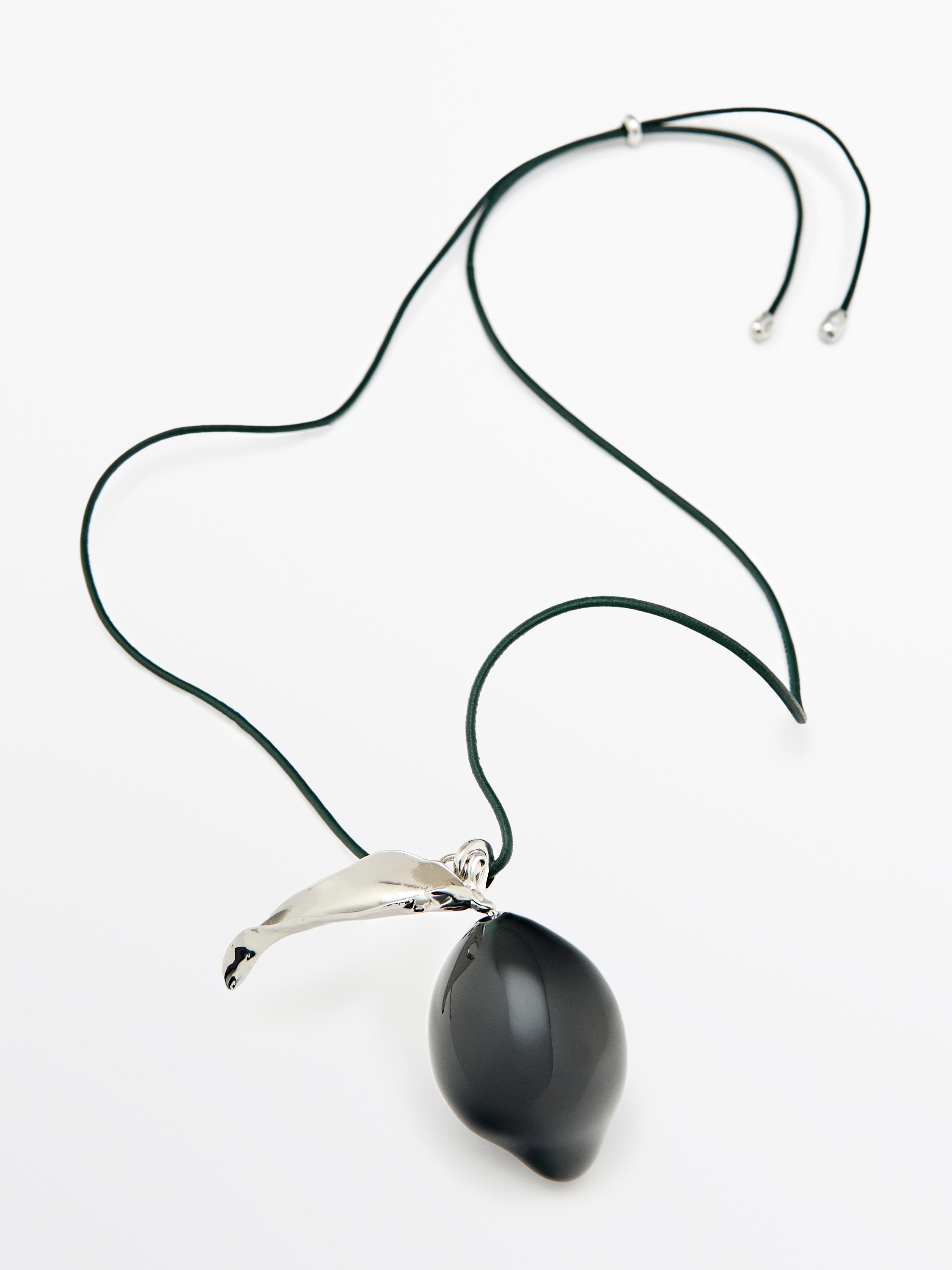 Siyah parçalı ve gümüş detaylı koyu renk kordonlu kolye.