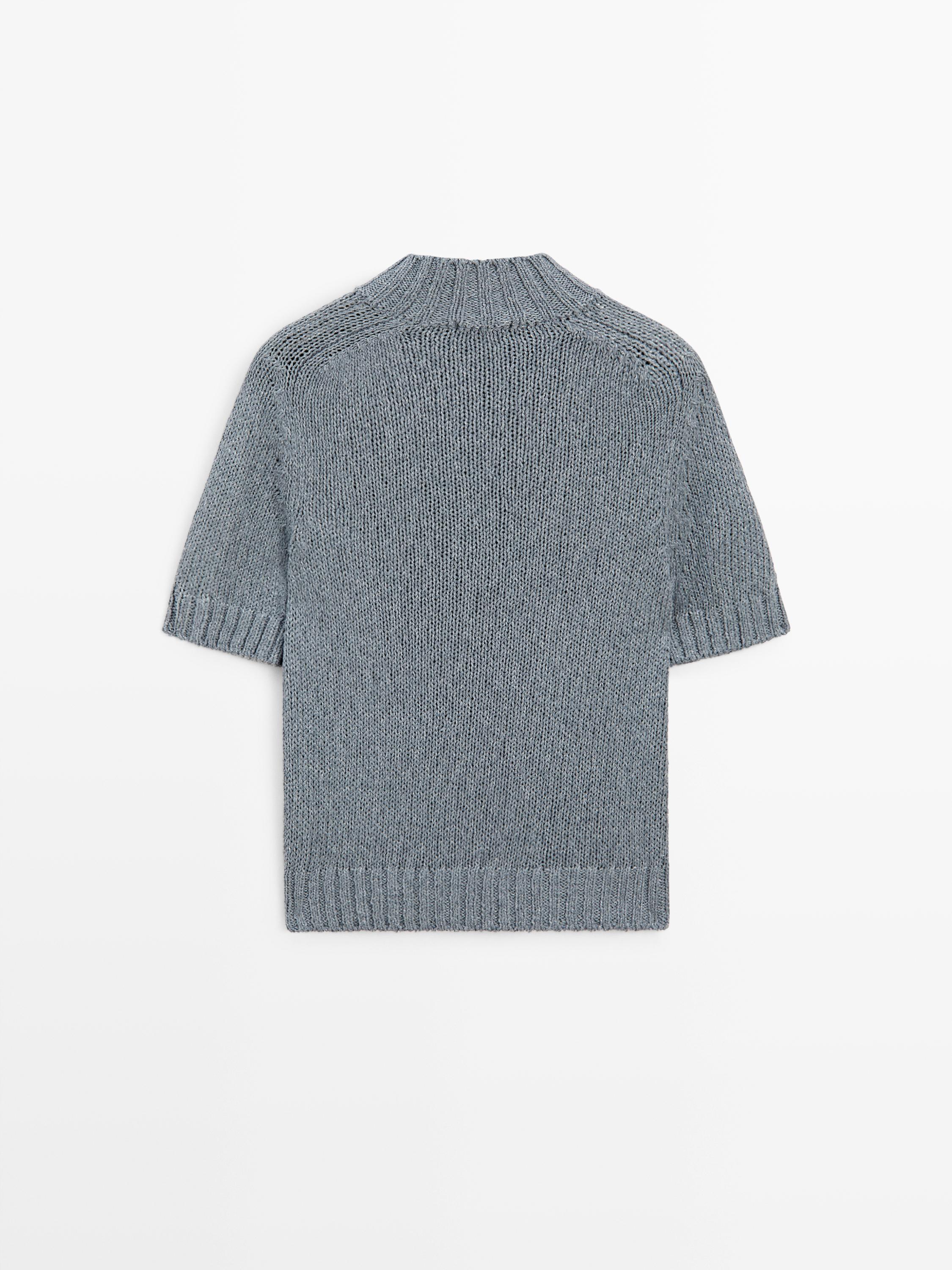 Vista posterior de suéter azul gris de punto con cuello perkins y mangas cortas.