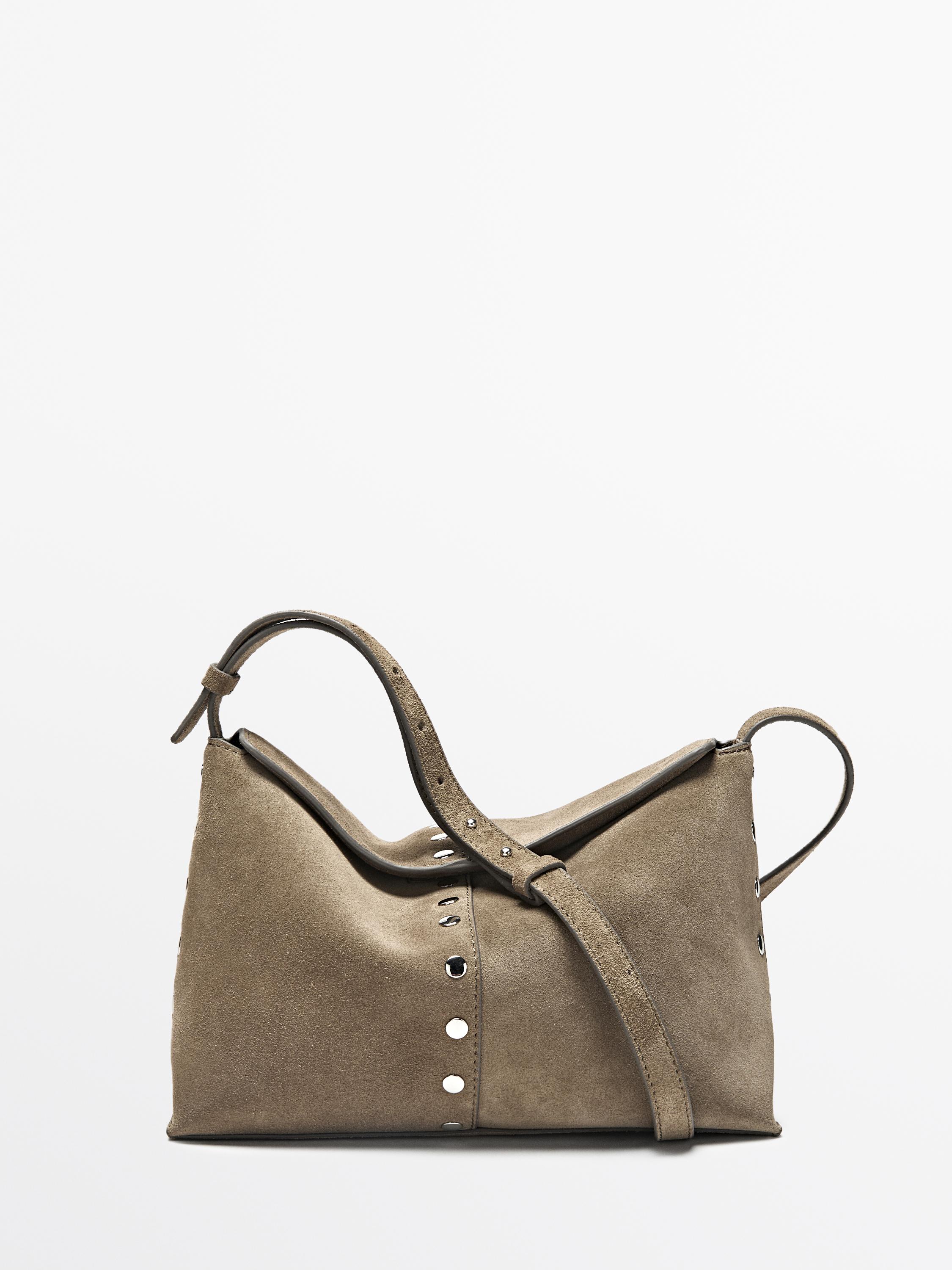 มุมมองด้านหน้าของกระเป๋าถือสีน้ำตาลอมเทา พร้อมหมุดโลหะและสายสะพายปรับได้