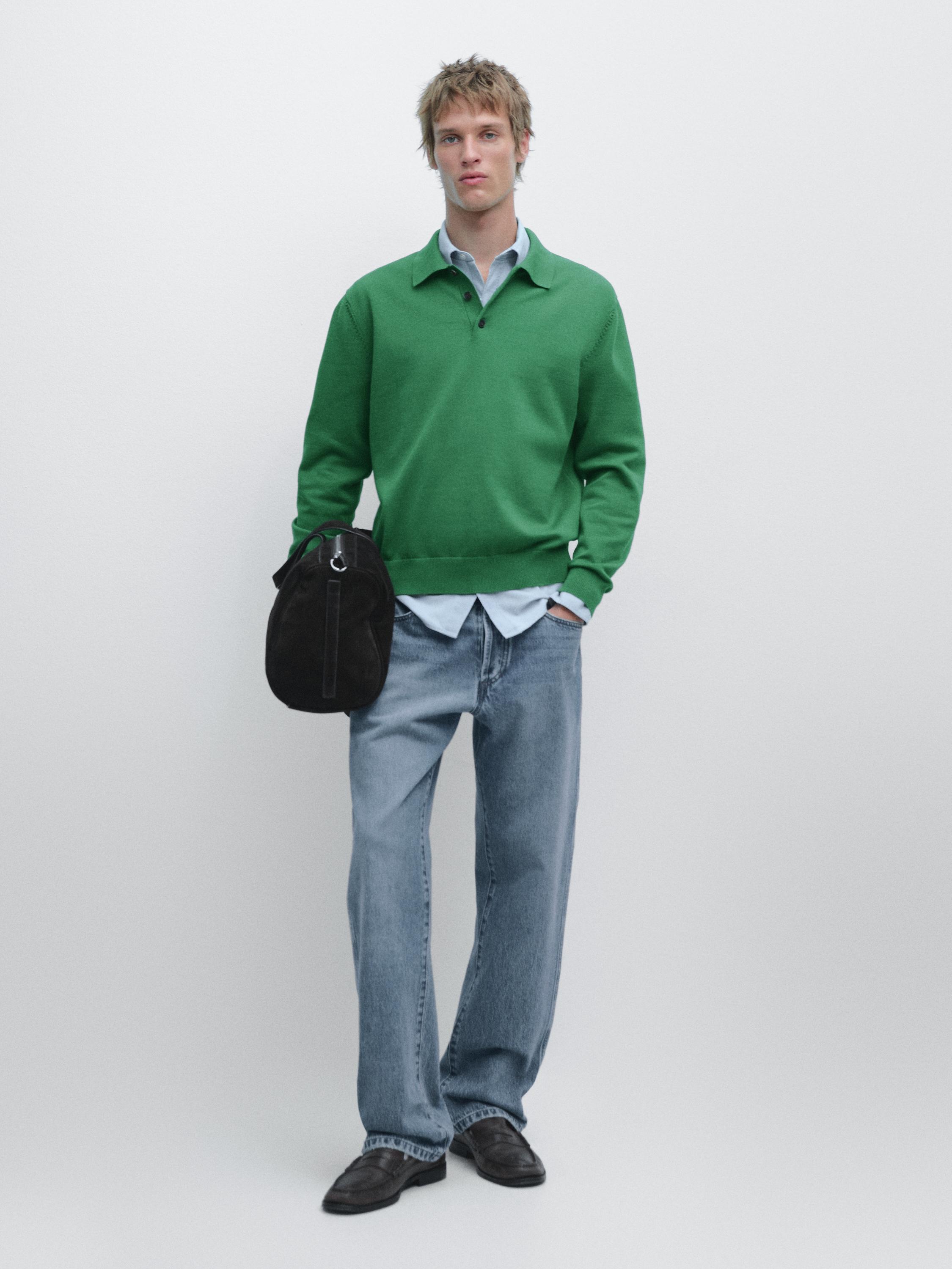 Set aus billardgrünem Polo-Pullover, hellblauem Hemd, blauen Jeans und schwarzen Schuhen.
