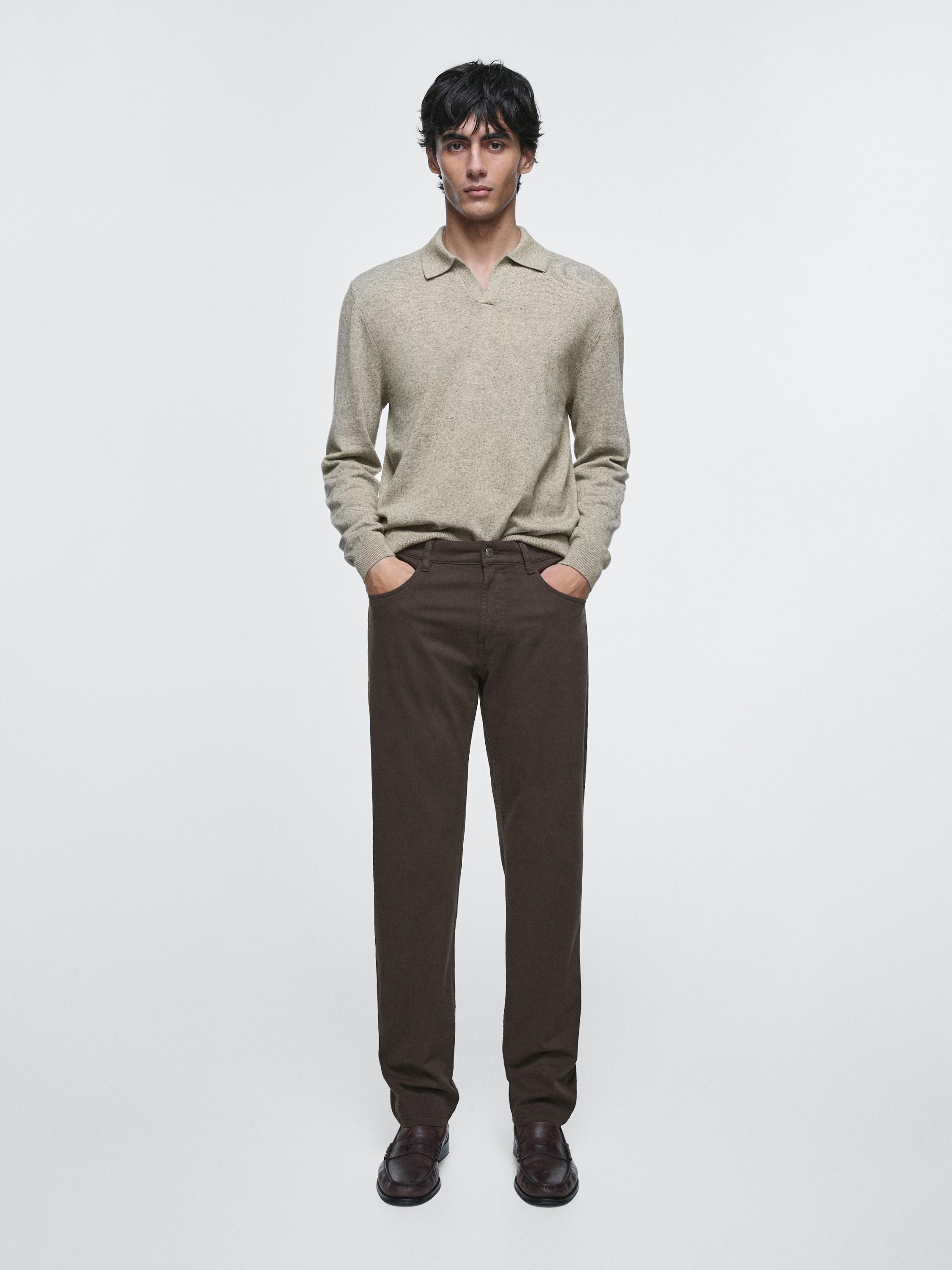 Ensemble composé d'un pull beige à manches longues et d'un jean marron de coupe tapered avec des poches latérales.