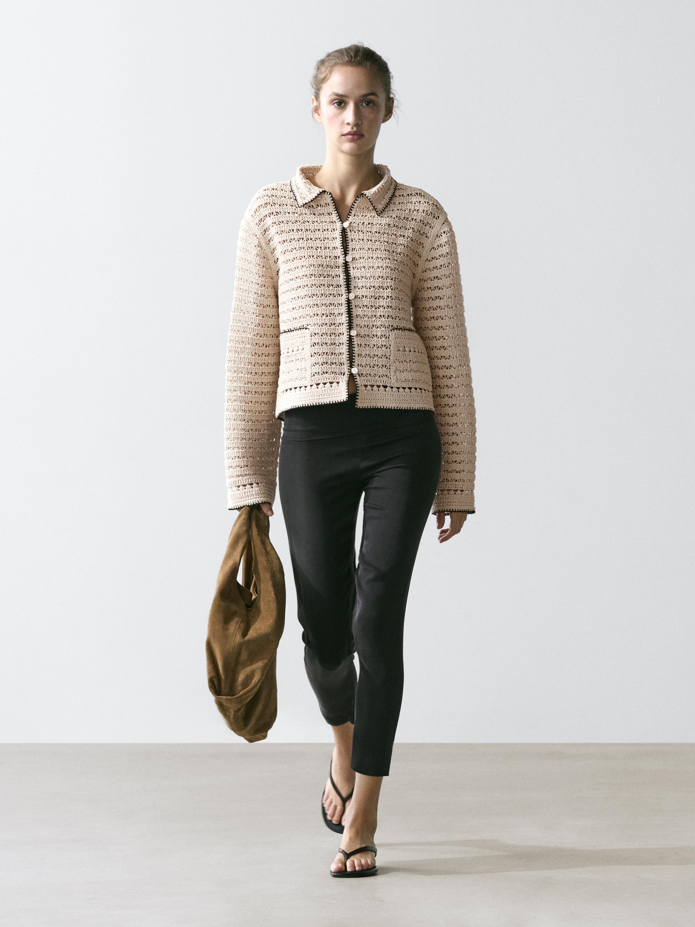 Beige cropped crochet jacket set with front pockets and black skinny pants.