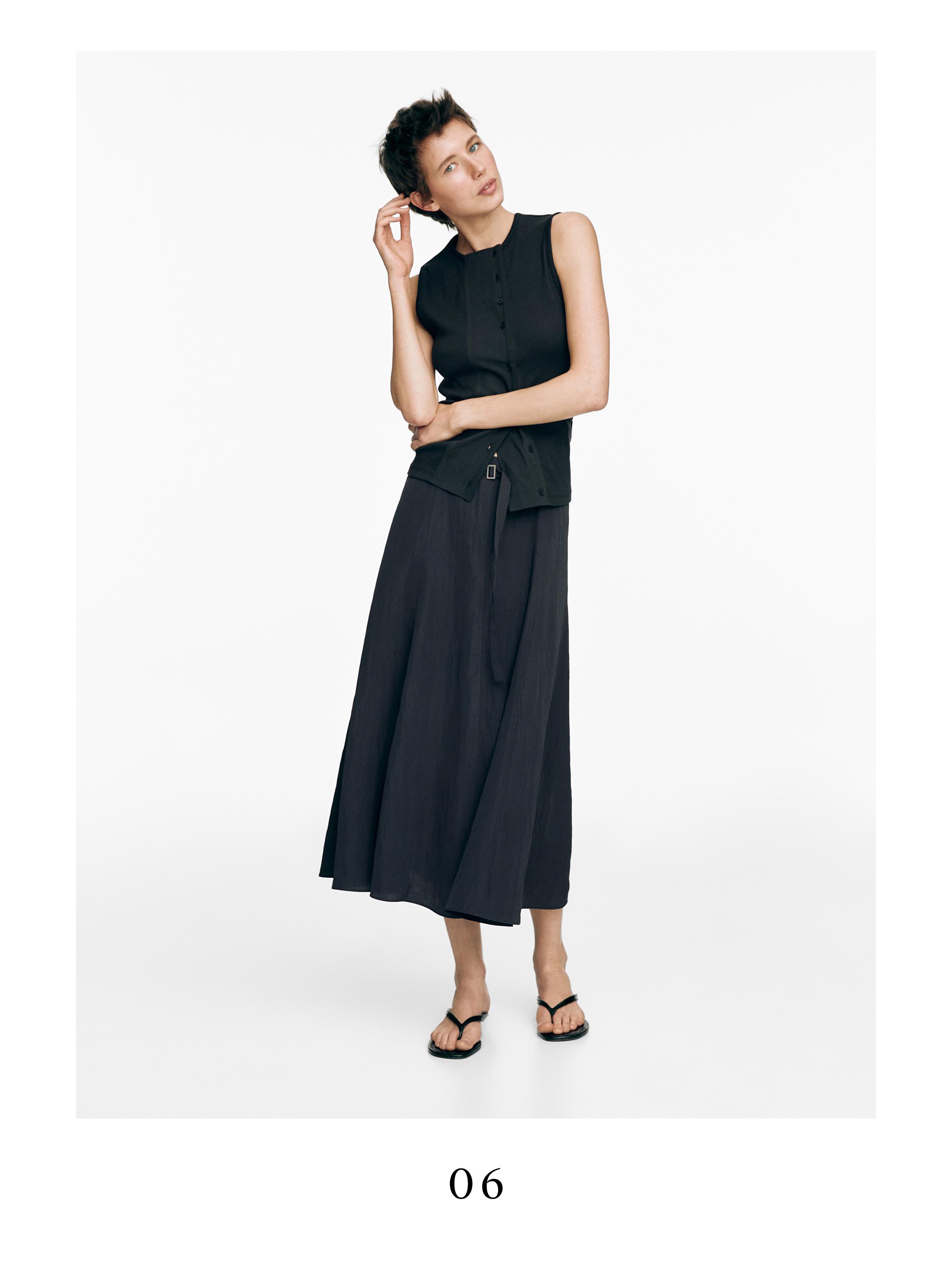 Μακρύ, γκρι-μπλε σετ φούστας με ζώνη και μαύρο αμάνικο τοπ με κουμπιά μπροστά.