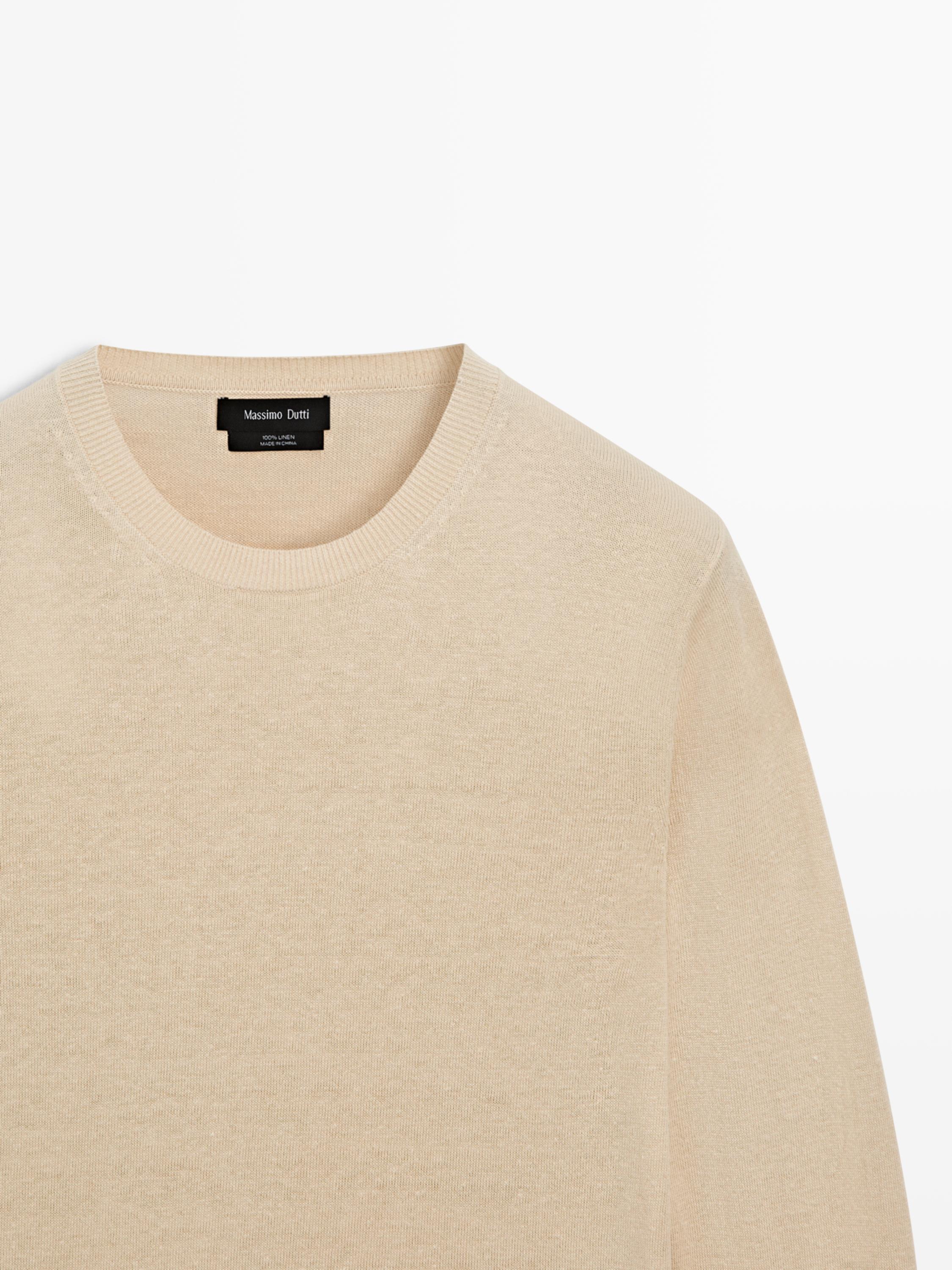 "Plano medio de jersey vainilla con cuello redondo. Etiqueta visible con texto 'Massimo Dutti'."