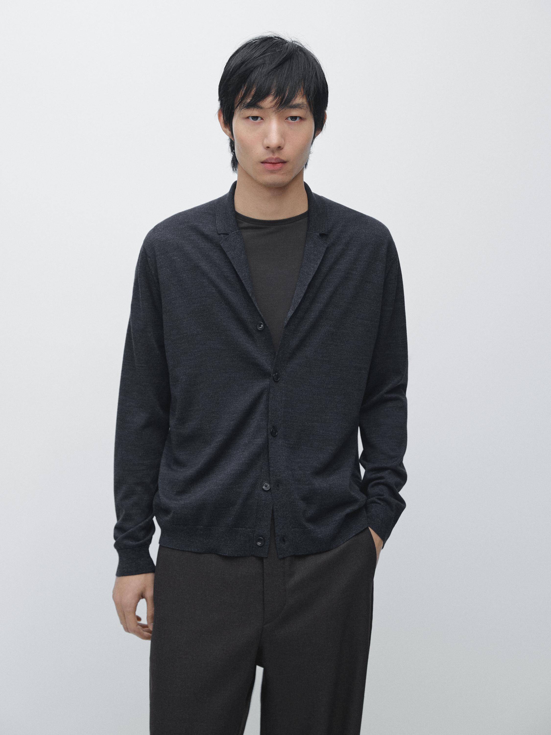 طقم كارديجان كحلي داكن بياقة مطوية وأزرار، فوق قميص داكن، وبنطال داكن.