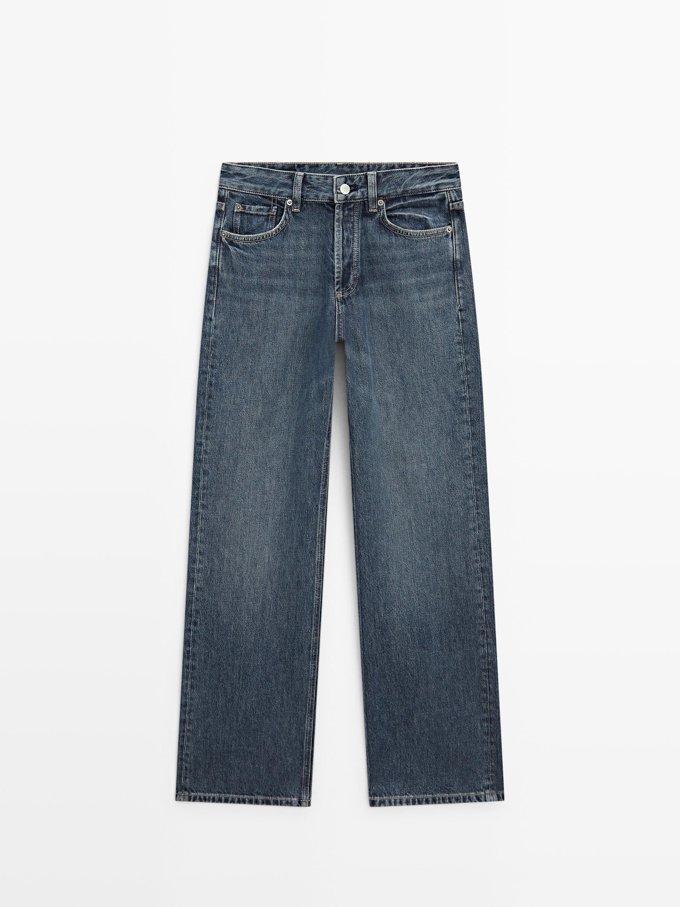 Frontal visning af mellemblå jeans med vide ben og mellemhøj talje, med synlige for- og baglommer.