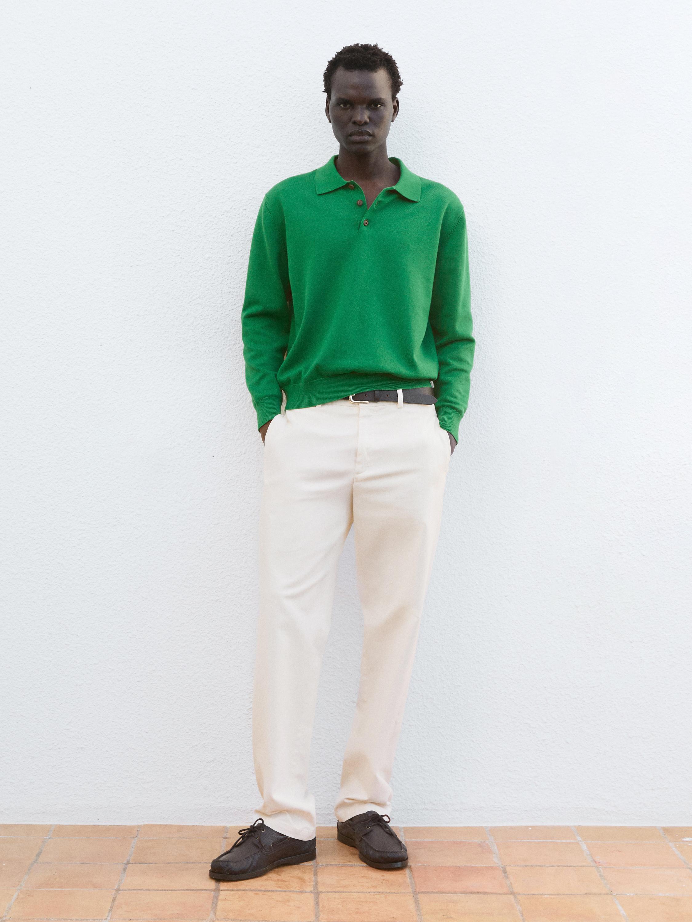 Conjunto de jersey verde con cuello y botones, pantalones beige rectos y zapatos marrones.