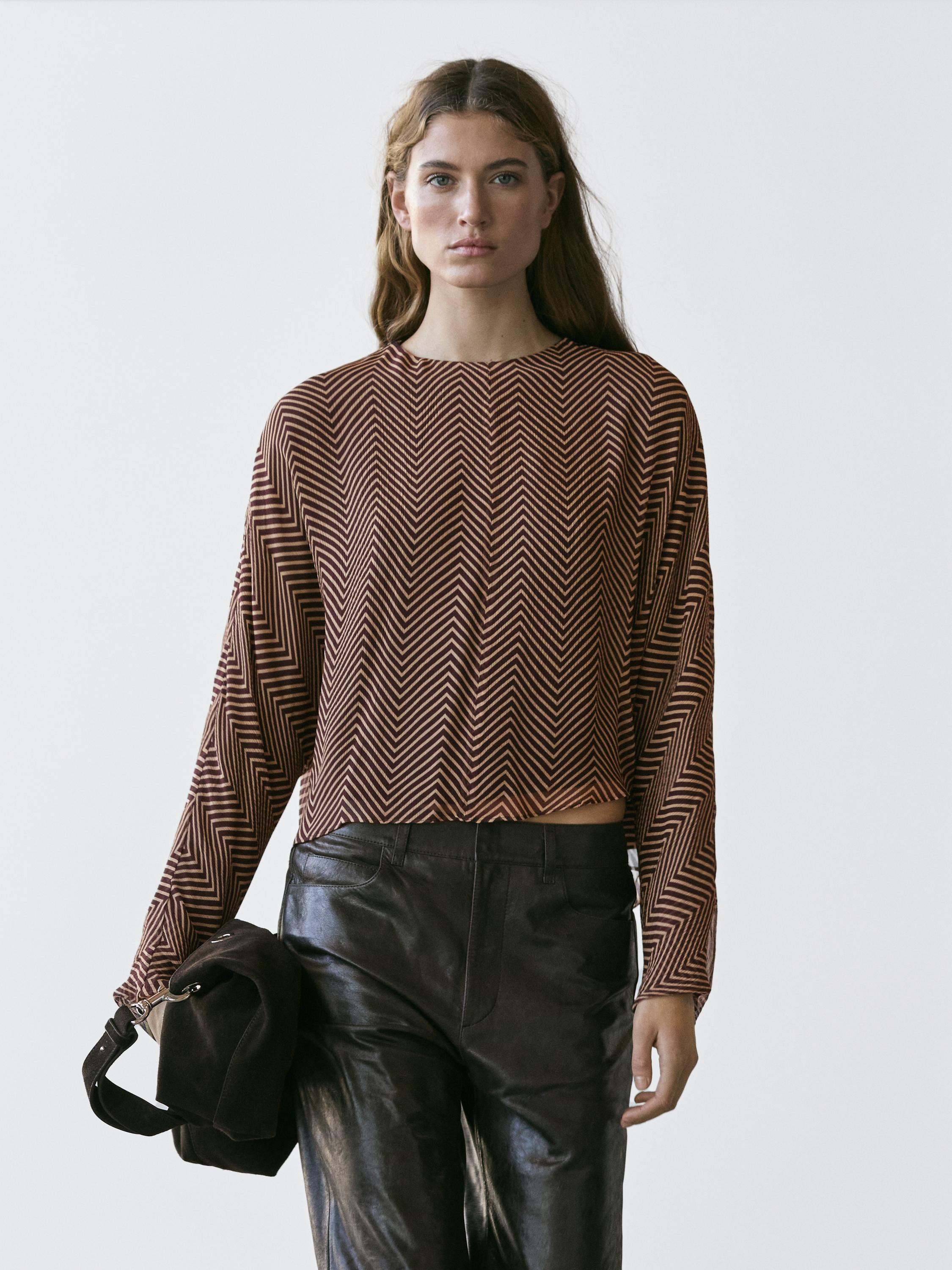 Conjunto de blusa burdeos con estampado geométrico y pantalones negros.