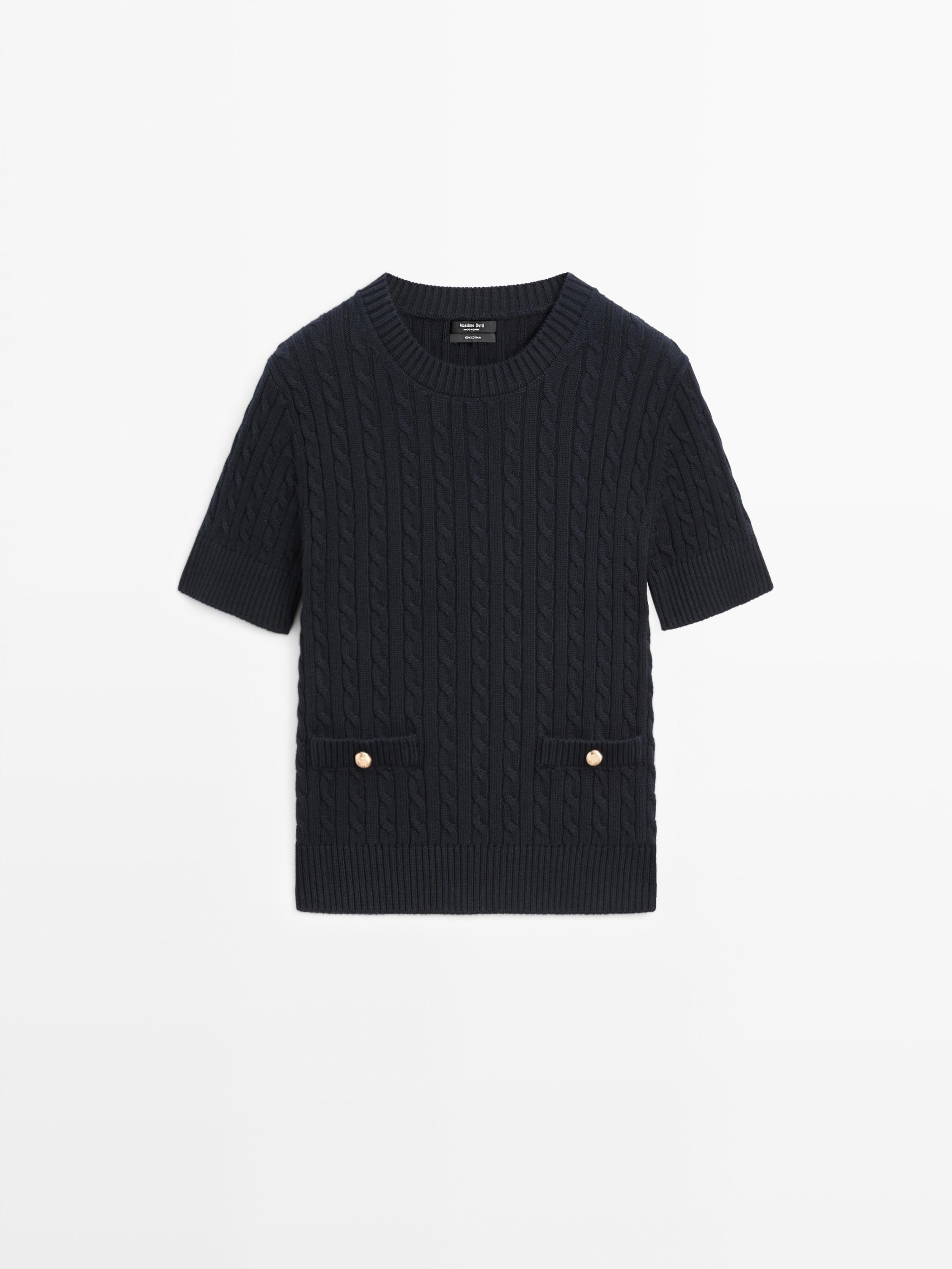 Front view of a navy blue cable knit short-sleeve sweater with front pockets and gold buttons.
