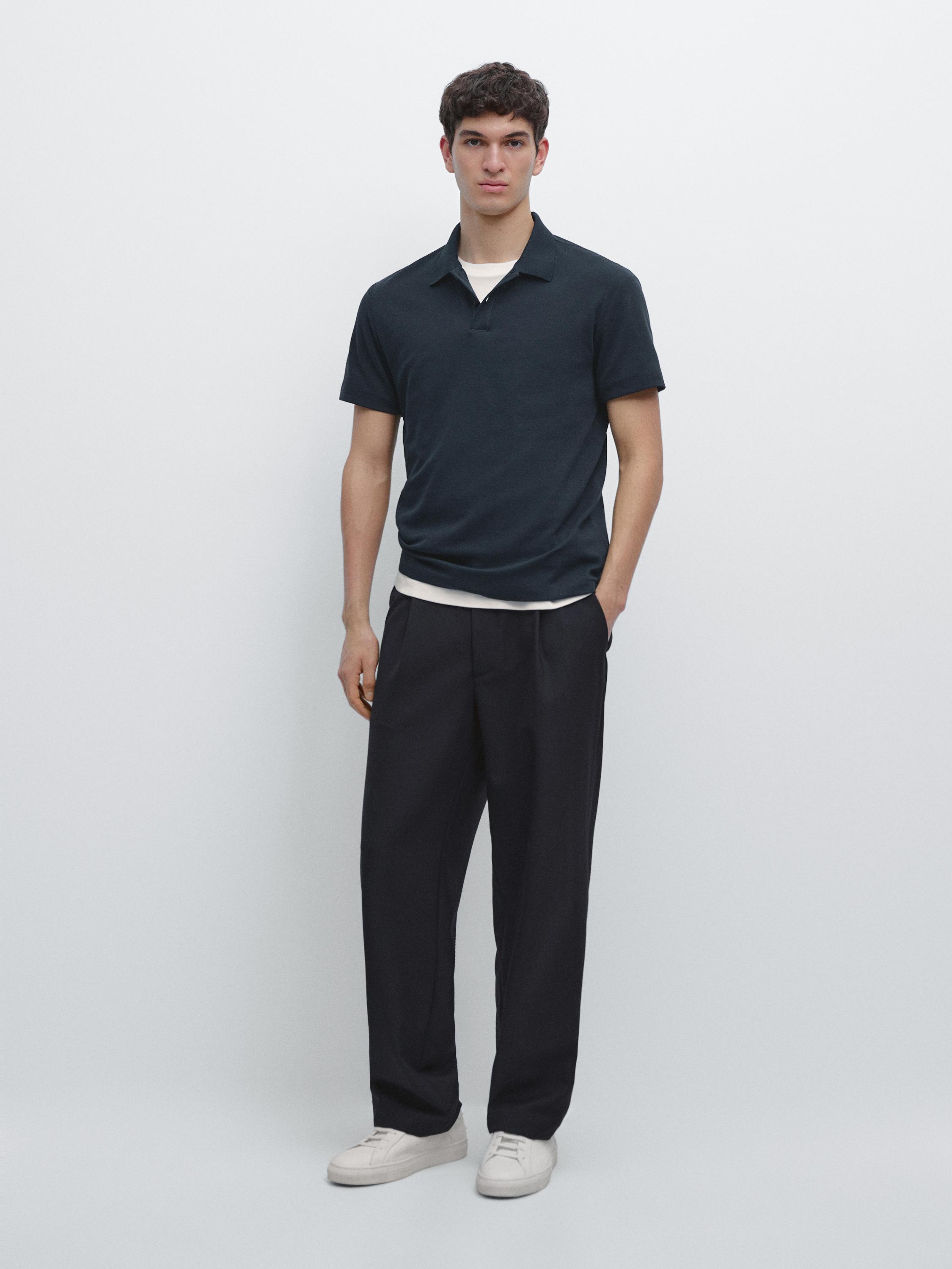 Conjunto de polo azul marino de manga corta y pantalón negro de corte recto con zapatillas blancas.